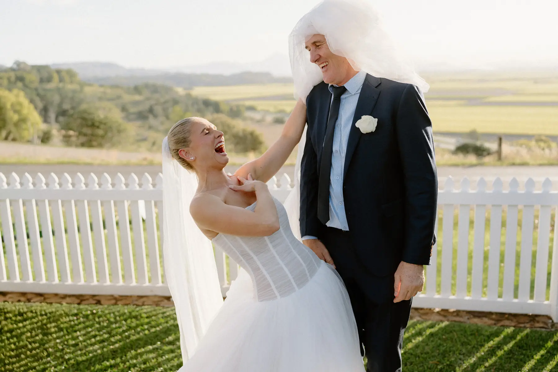 Laughing with a guest by the white picket fence, Botanica Plantation House
