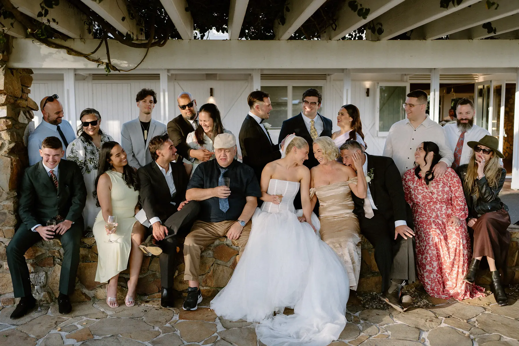 The stone verandah crowded with guests mid-laugh, Botanica Plantation House