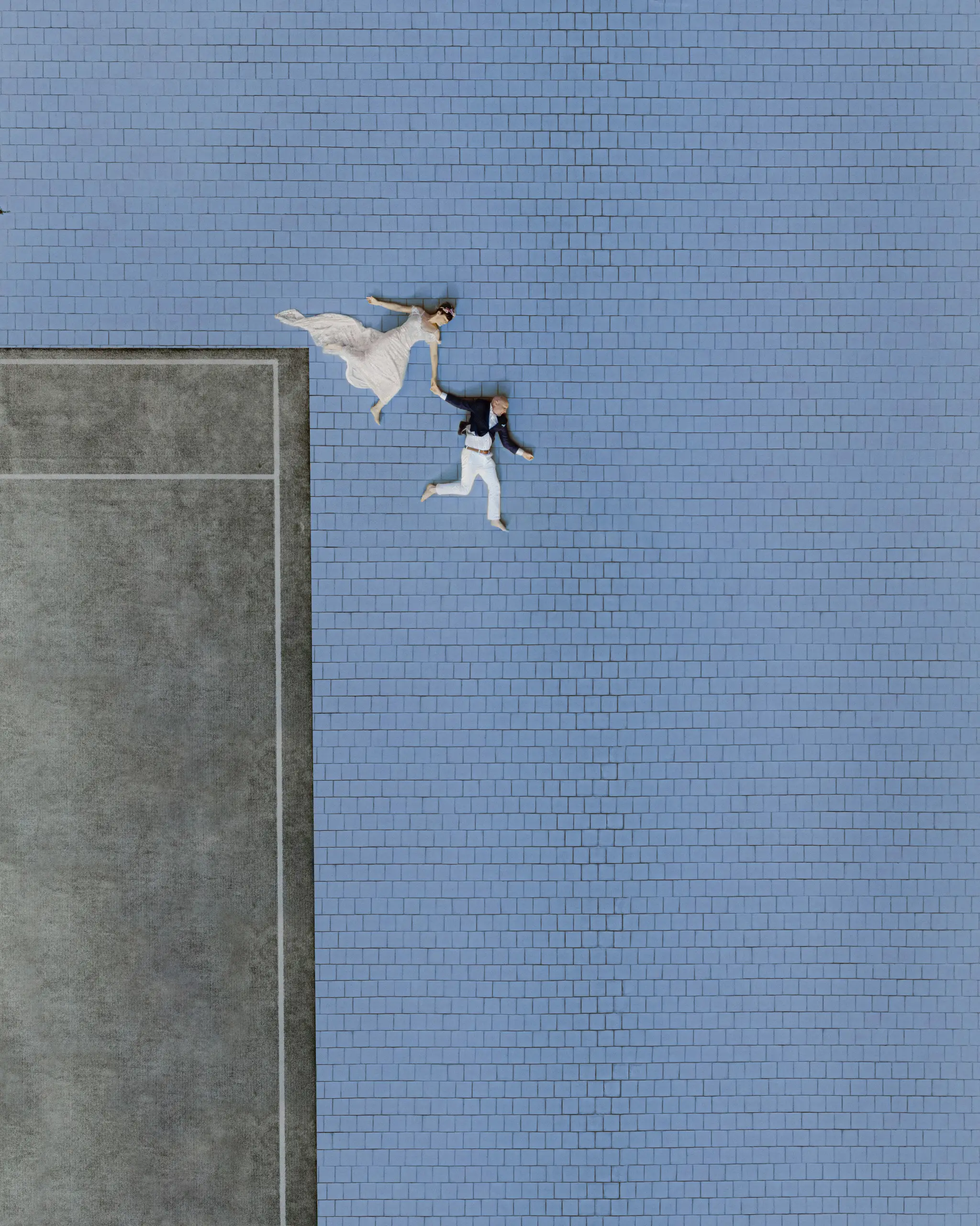 Aerial frame of the couple crossing a blue-tiled rooftop