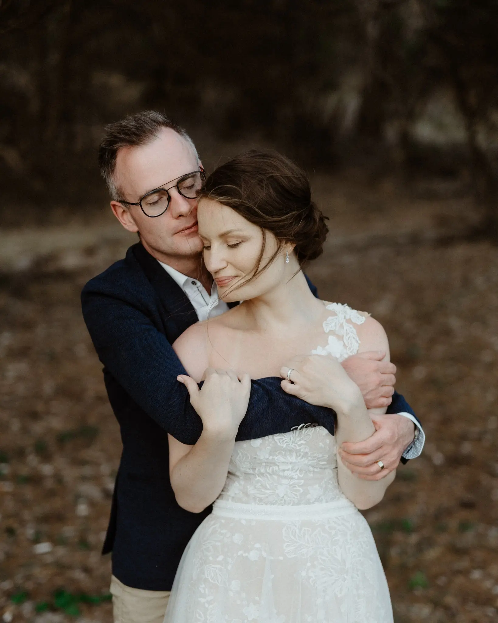 Groom wrapping the bride from behind among the dunes