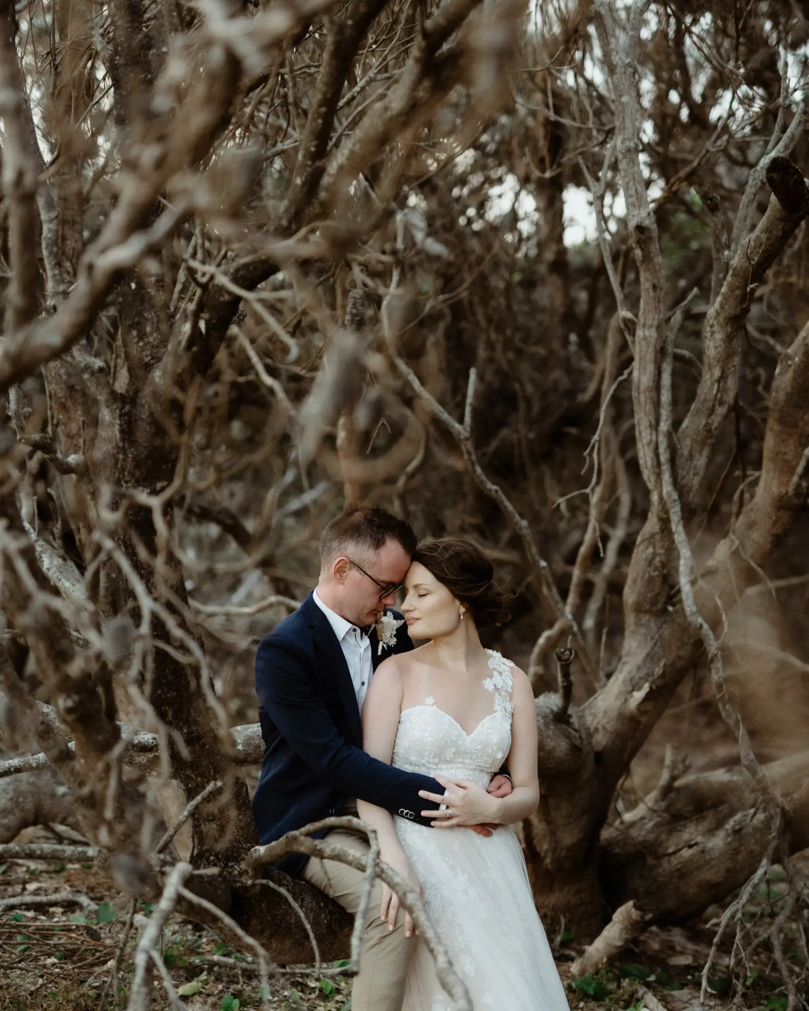 Couple sheltered in a thicket of wind-bent coastal tea-trees