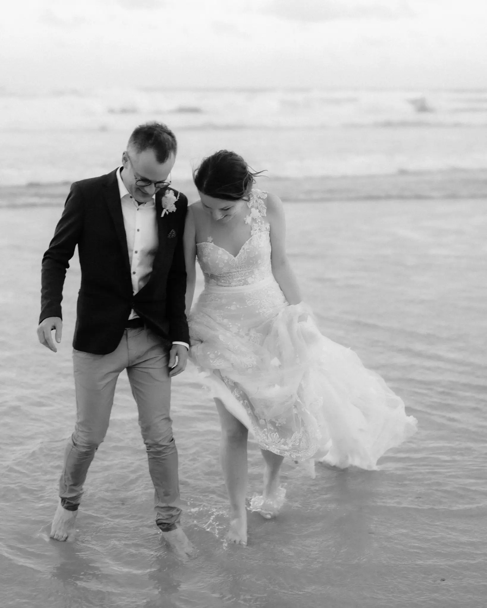 Couple mid-stride through the shallows, in black and white