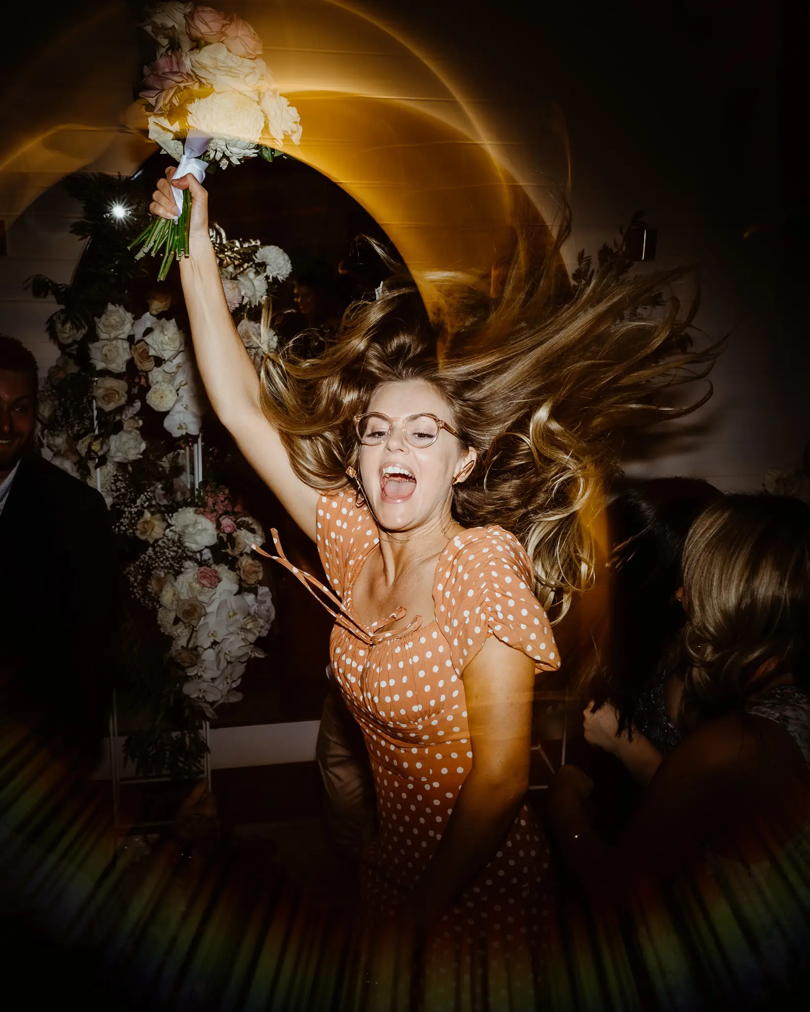 Guest mid-dance with the caught bouquet, hair flying
