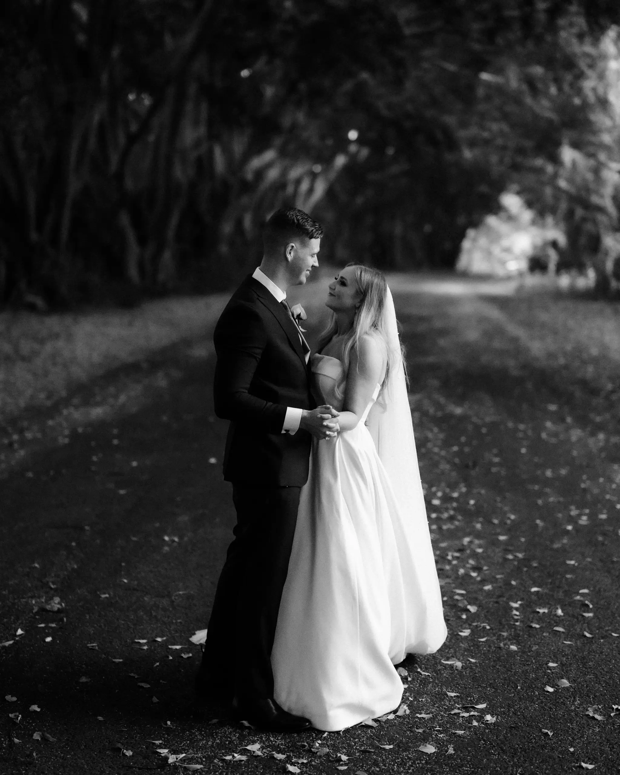 Couple on a tree-lined drive, in black and white
