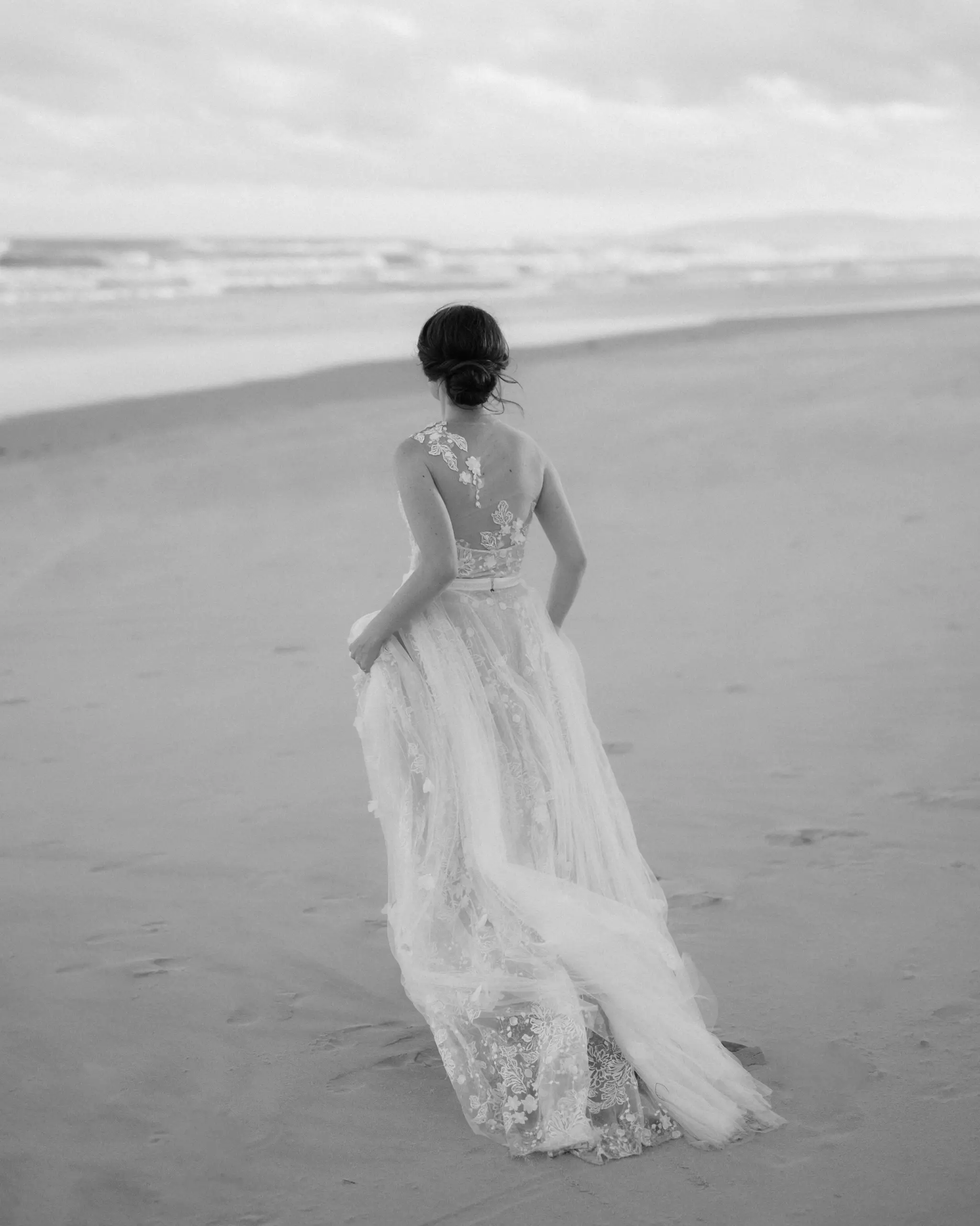 Bride walking a pale, empty beach