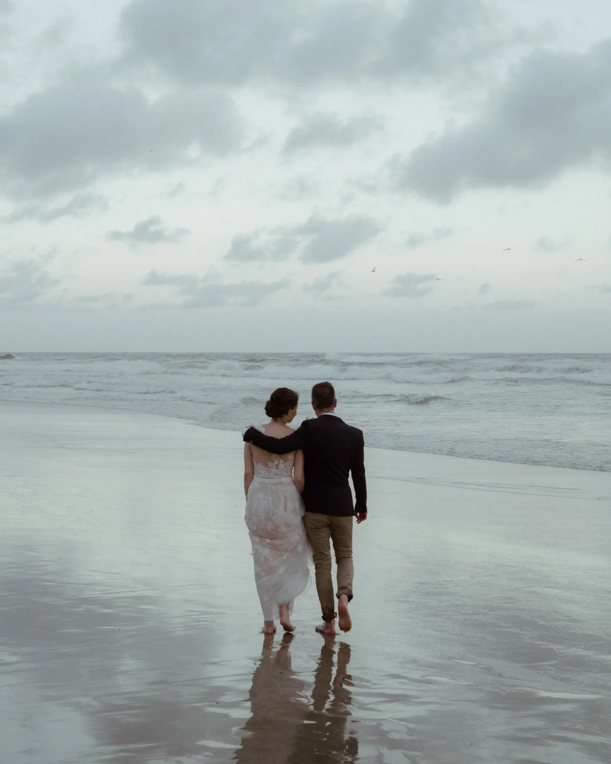 Couple walking the wet sand toward the waves