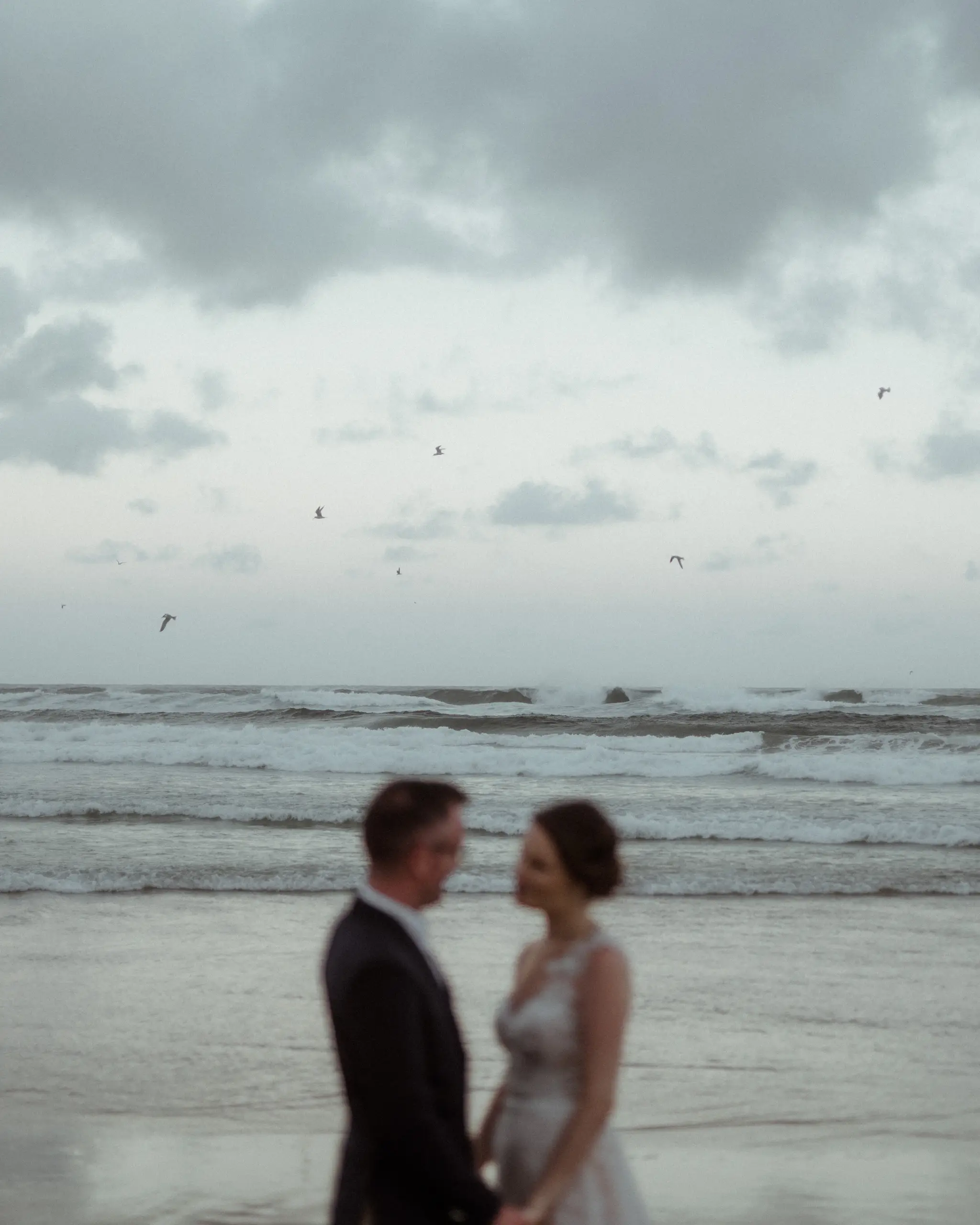Couple standing in the shallows under a brooding sky