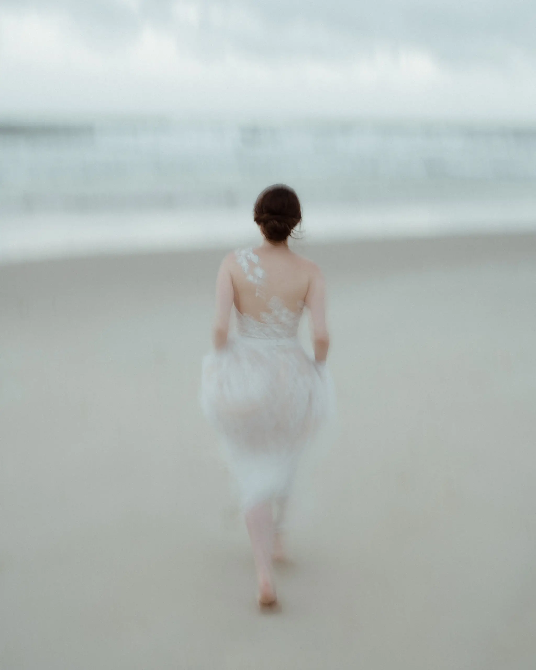Bride mid-step on the beach, dress blurred with motion