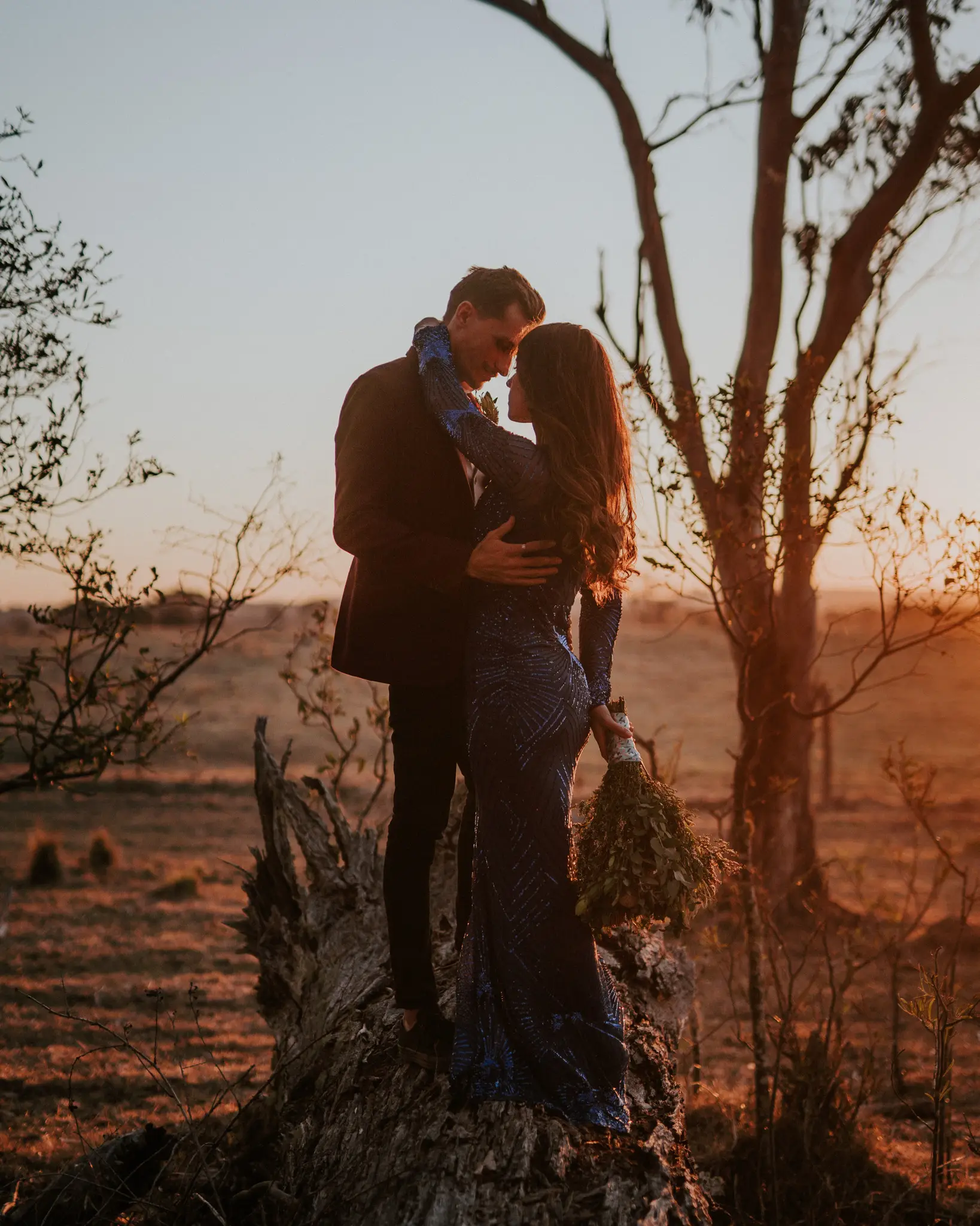 Couple on a rocky outcrop in burnt-orange sunset country