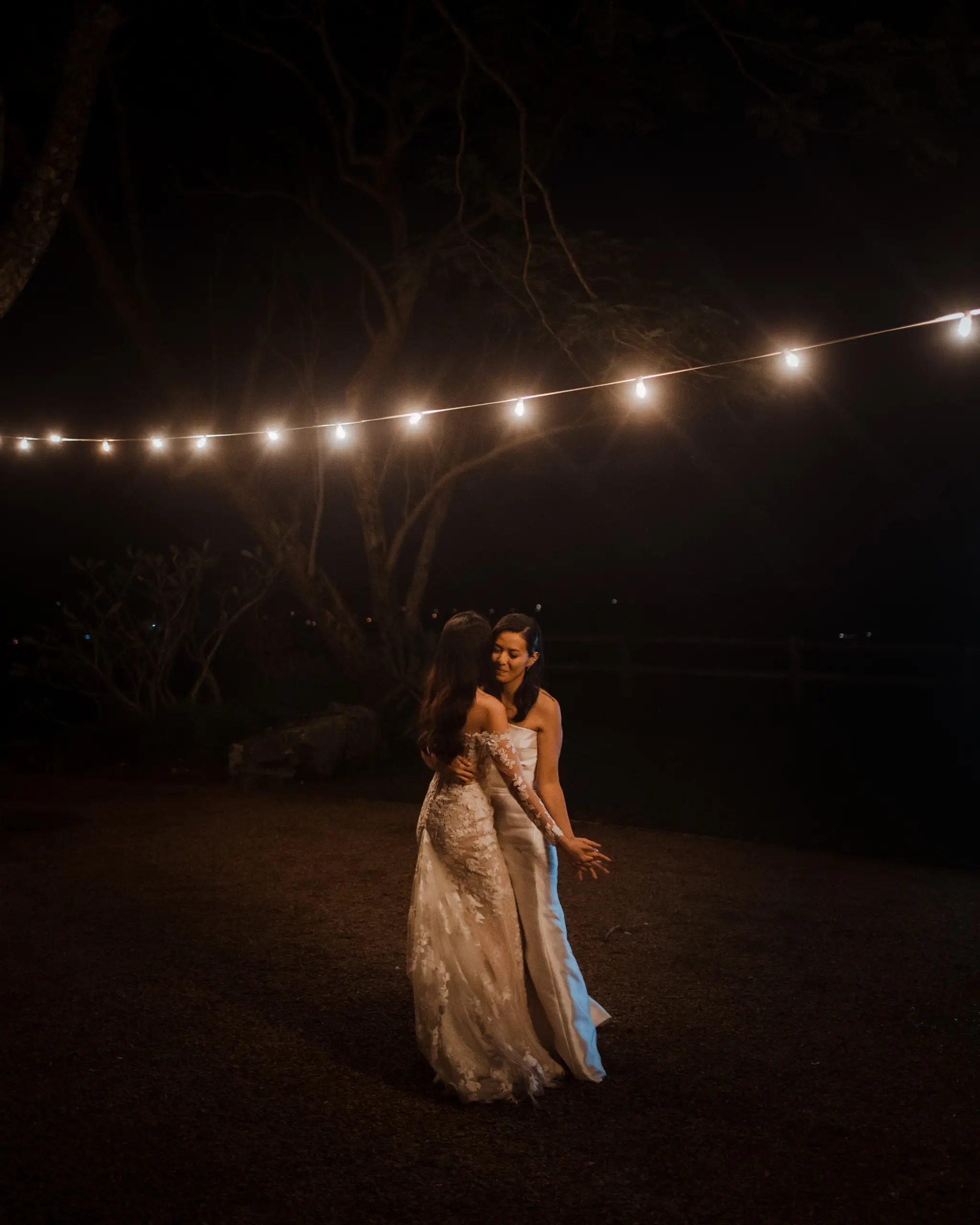 Bride walking beneath festoon lights at night