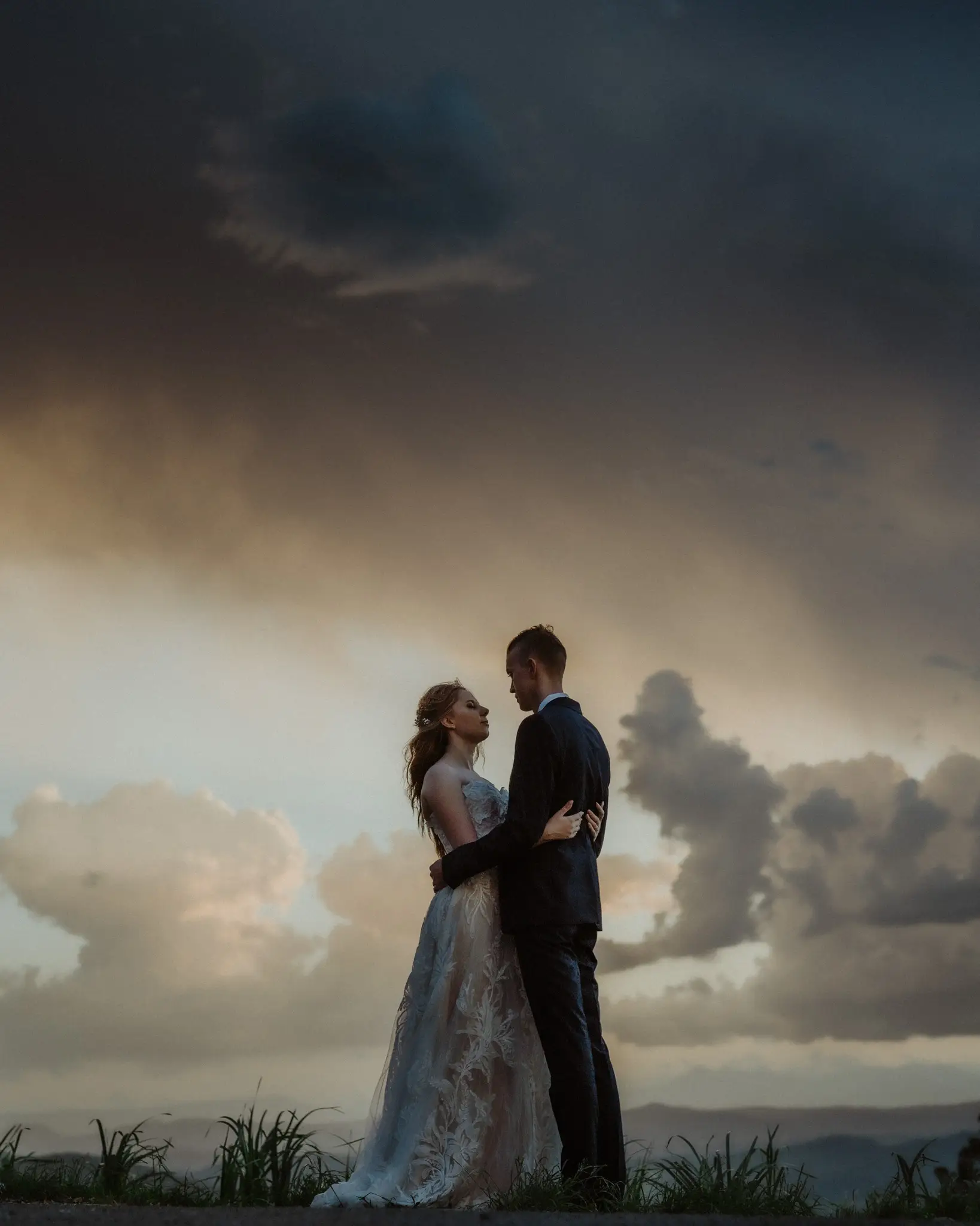 Couple against a bank of storm clouds at dusk