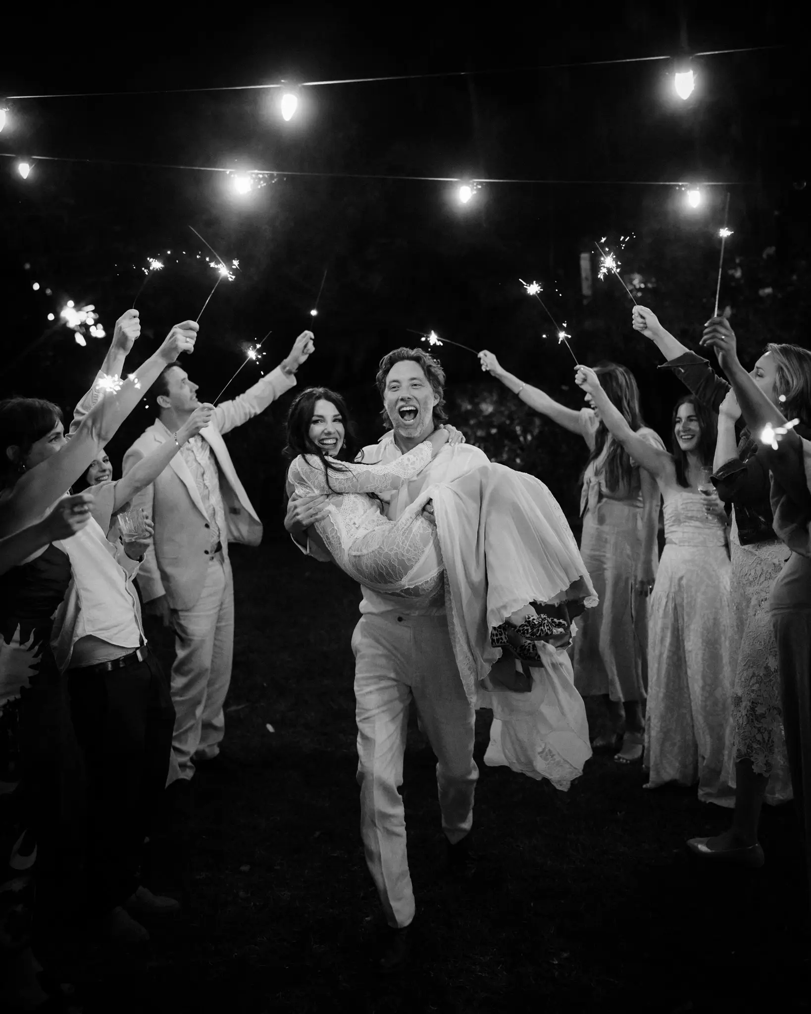 Sparkler exit with the bride carried through the crowd, in black and white