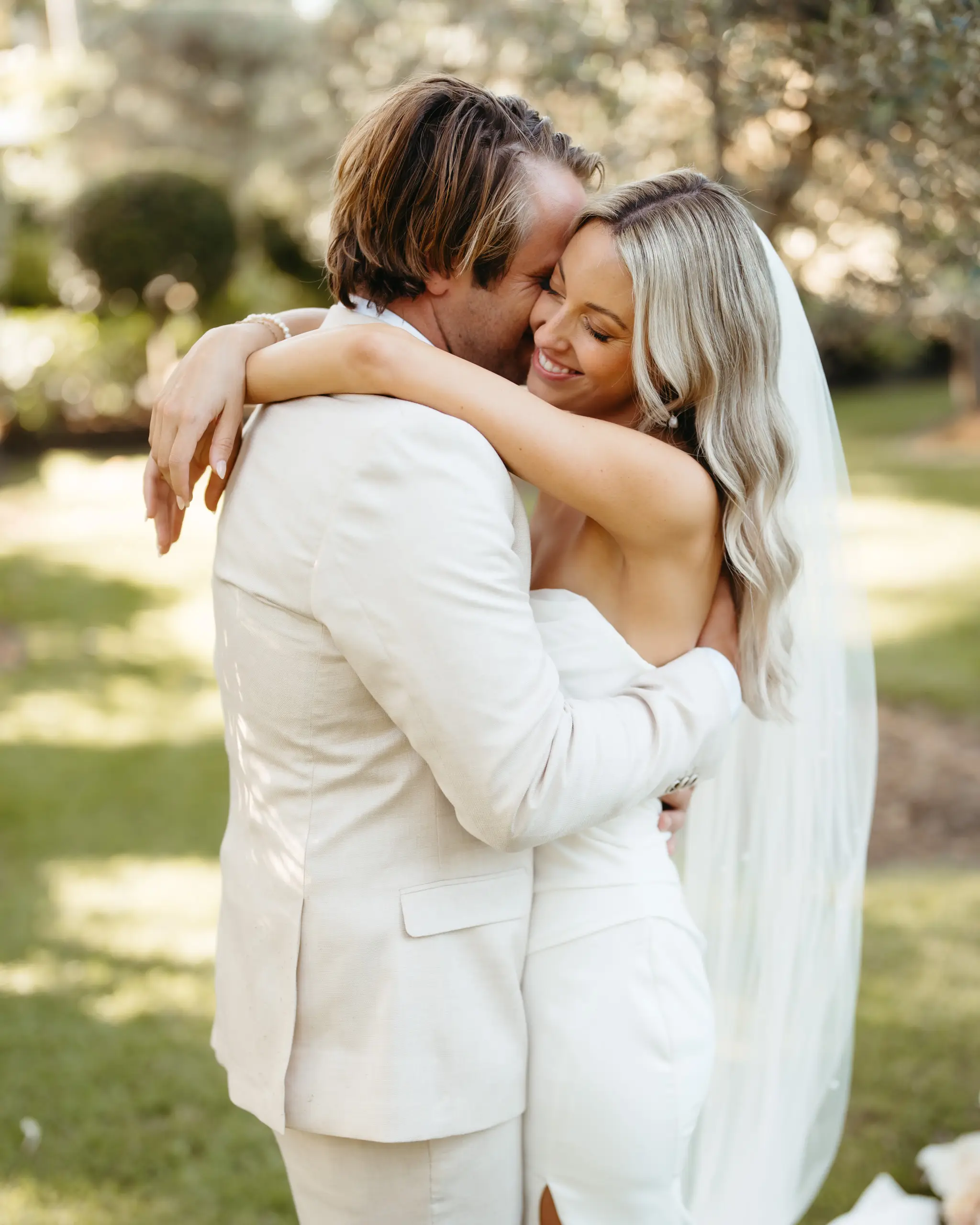Groom in cream linen holding the bride close