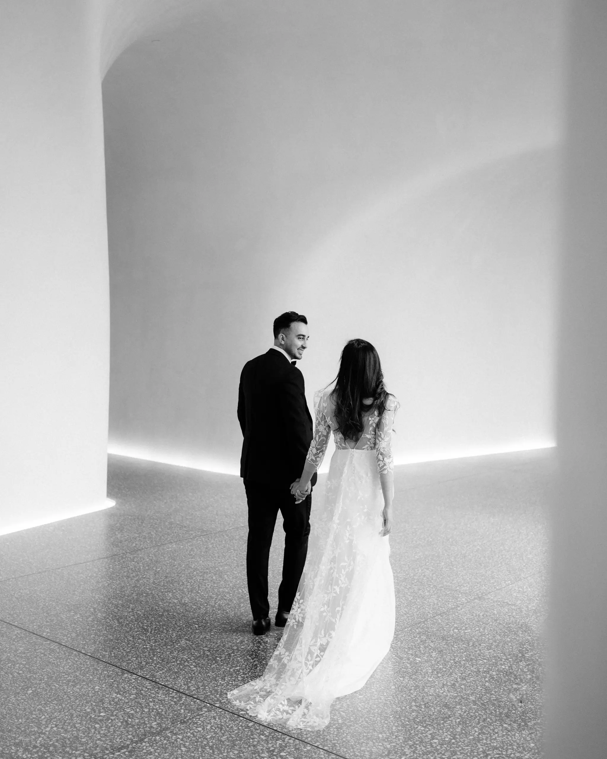 Couple in a white gallery space lit by a single strip of light