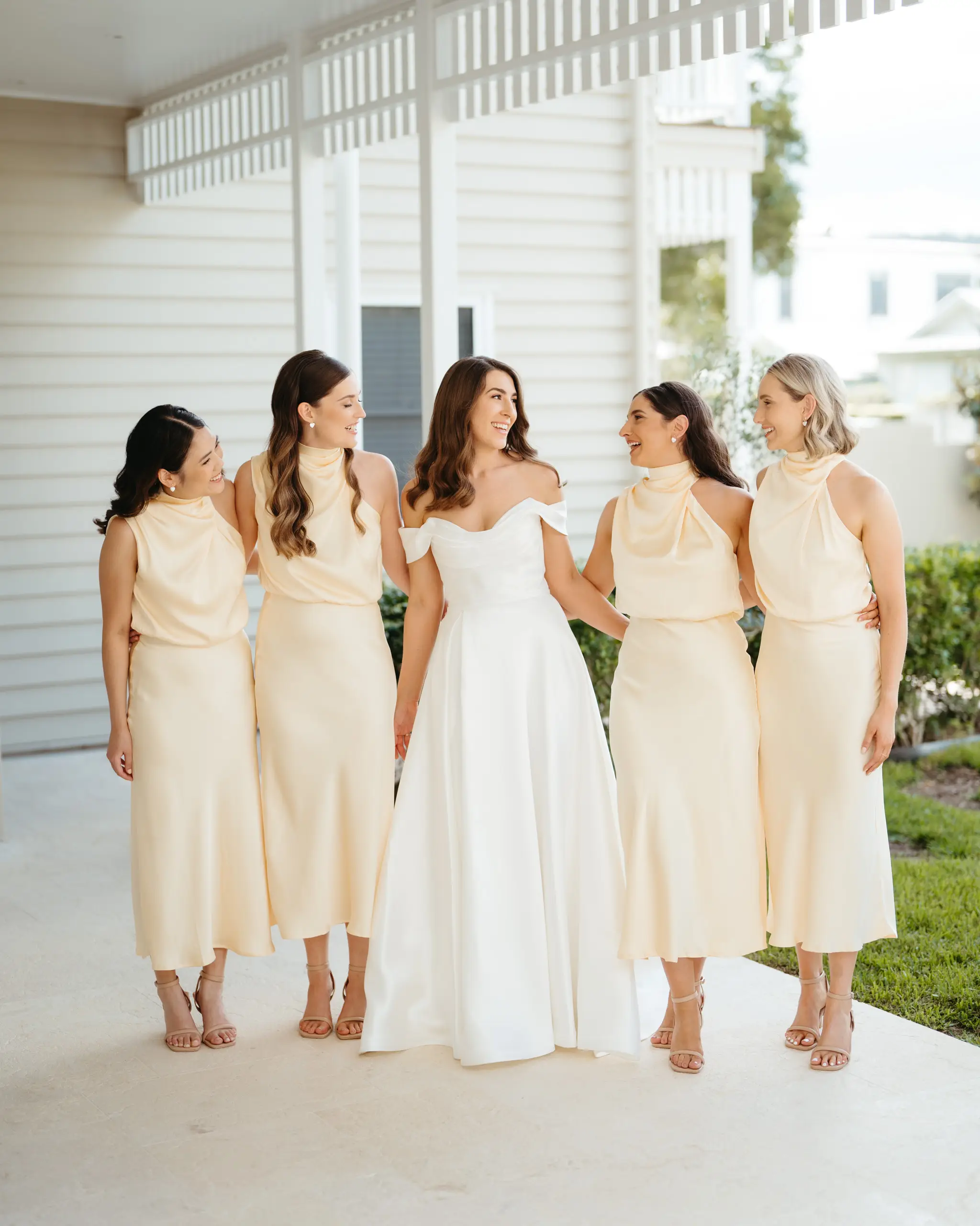 Bride laughing with her bridesmaids in champagne silk