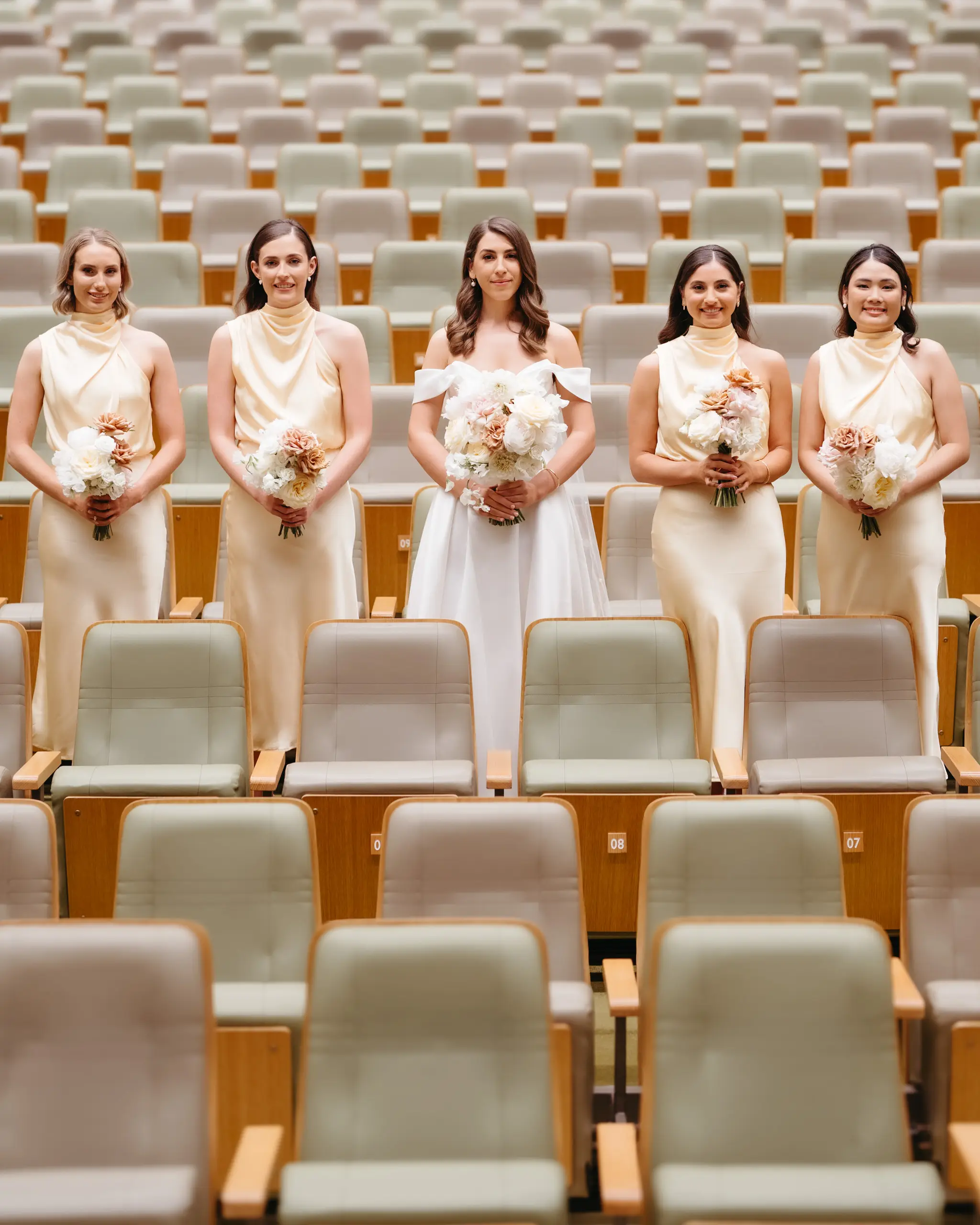 The bridal party seated in the rows of an empty auditorium