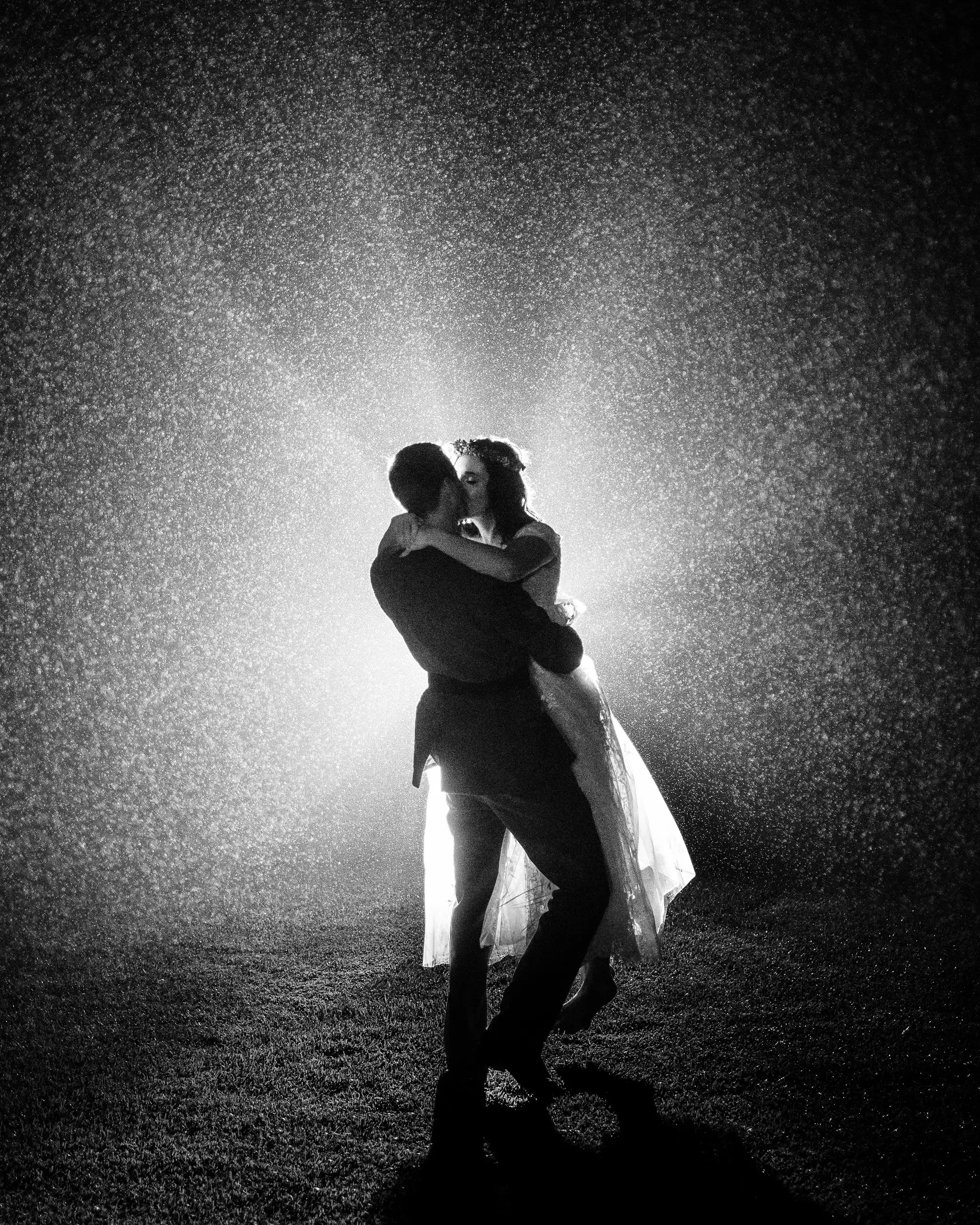 A backlit kiss in heavy rain at night