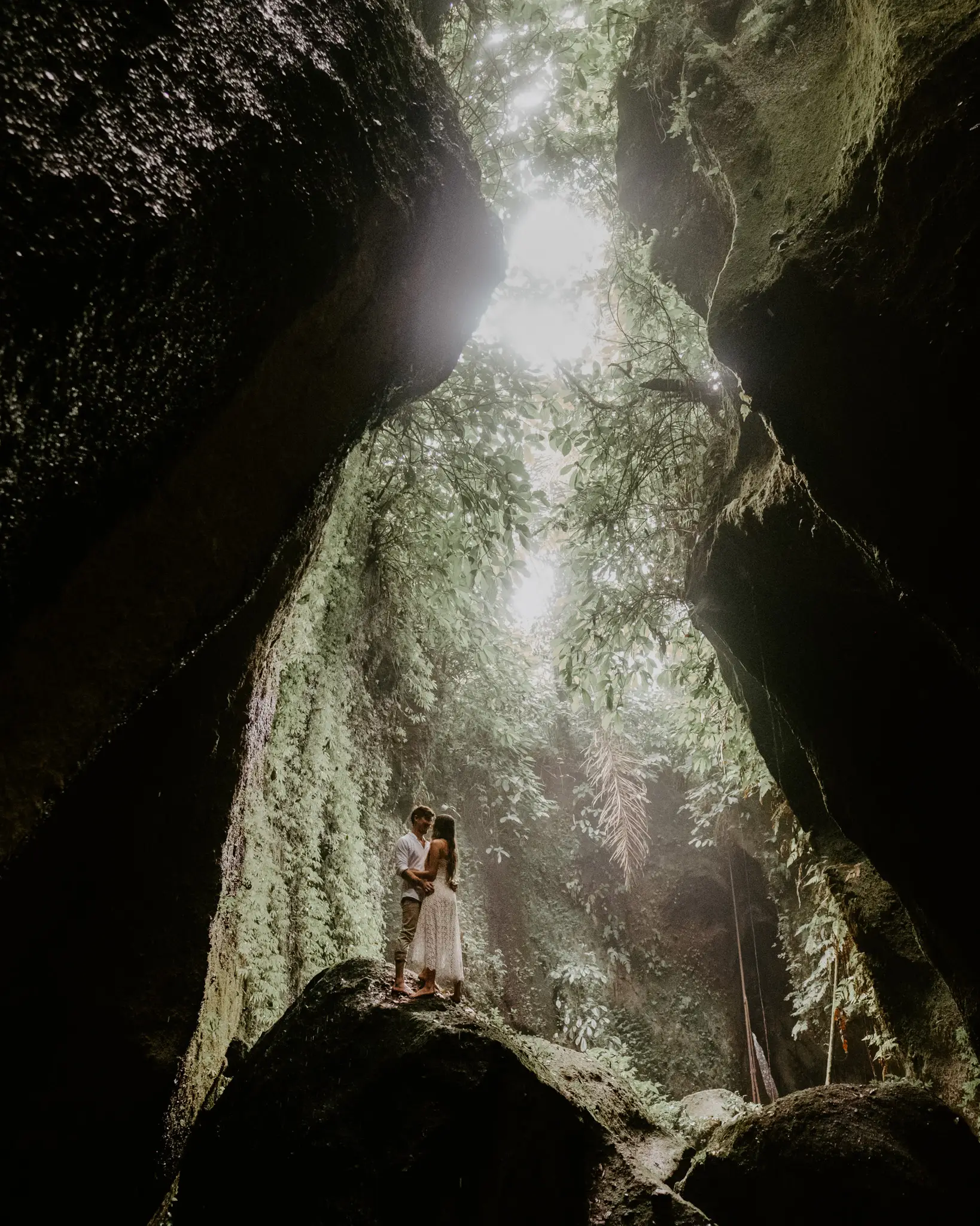 Bride on a mossy boulder deep in a green gorge