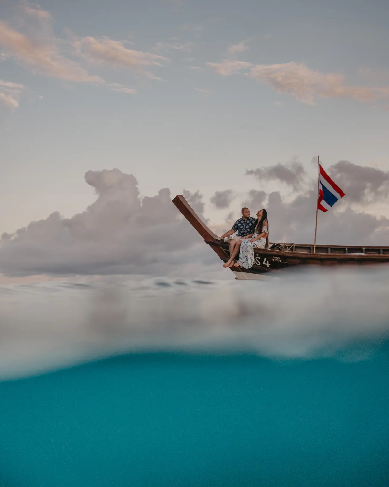 Couple on the bow of a longtail boat, split above and below the waterline, Thailand