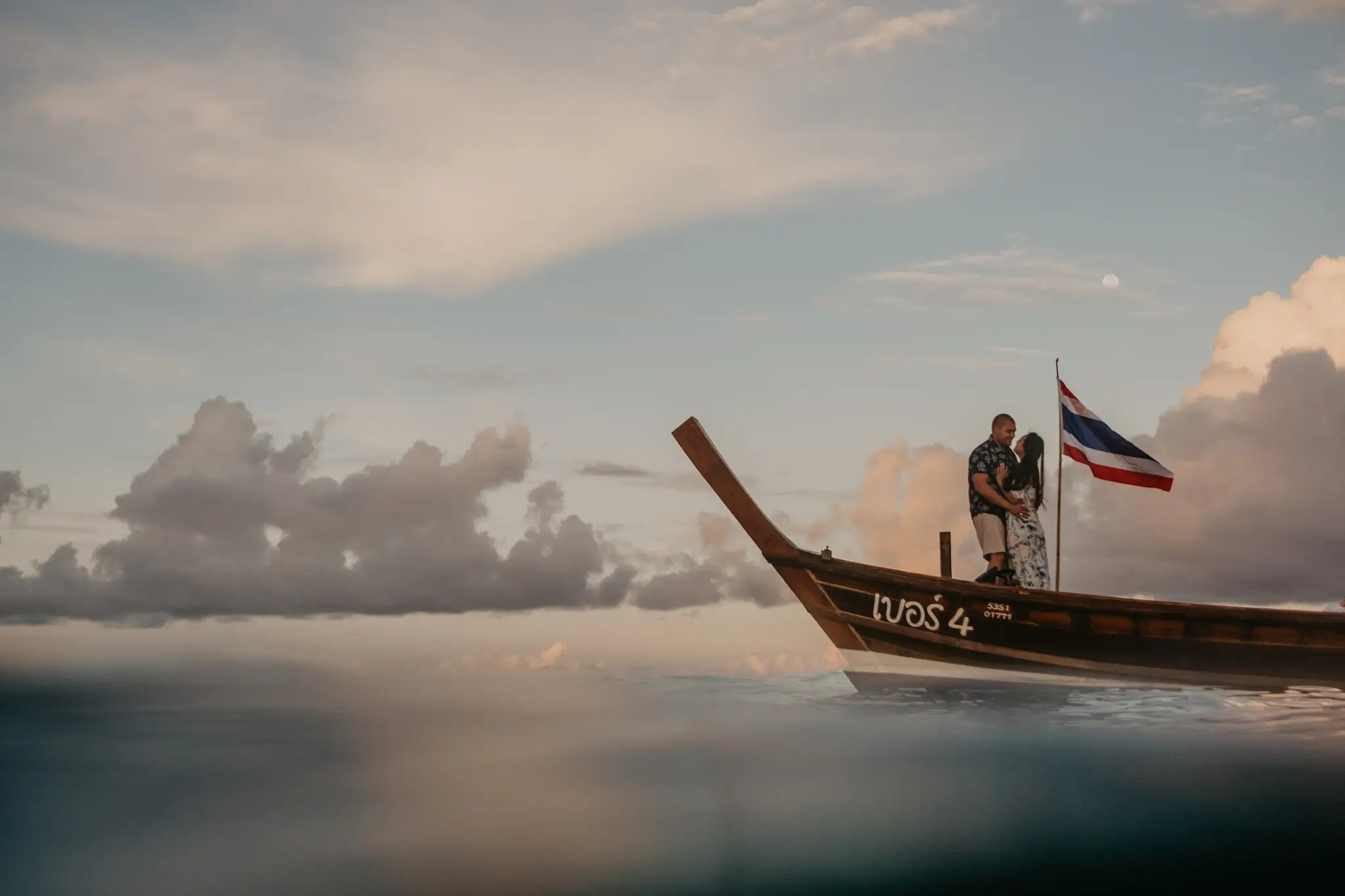 Longtail boat at anchor on glassy water at dusk, Thailand