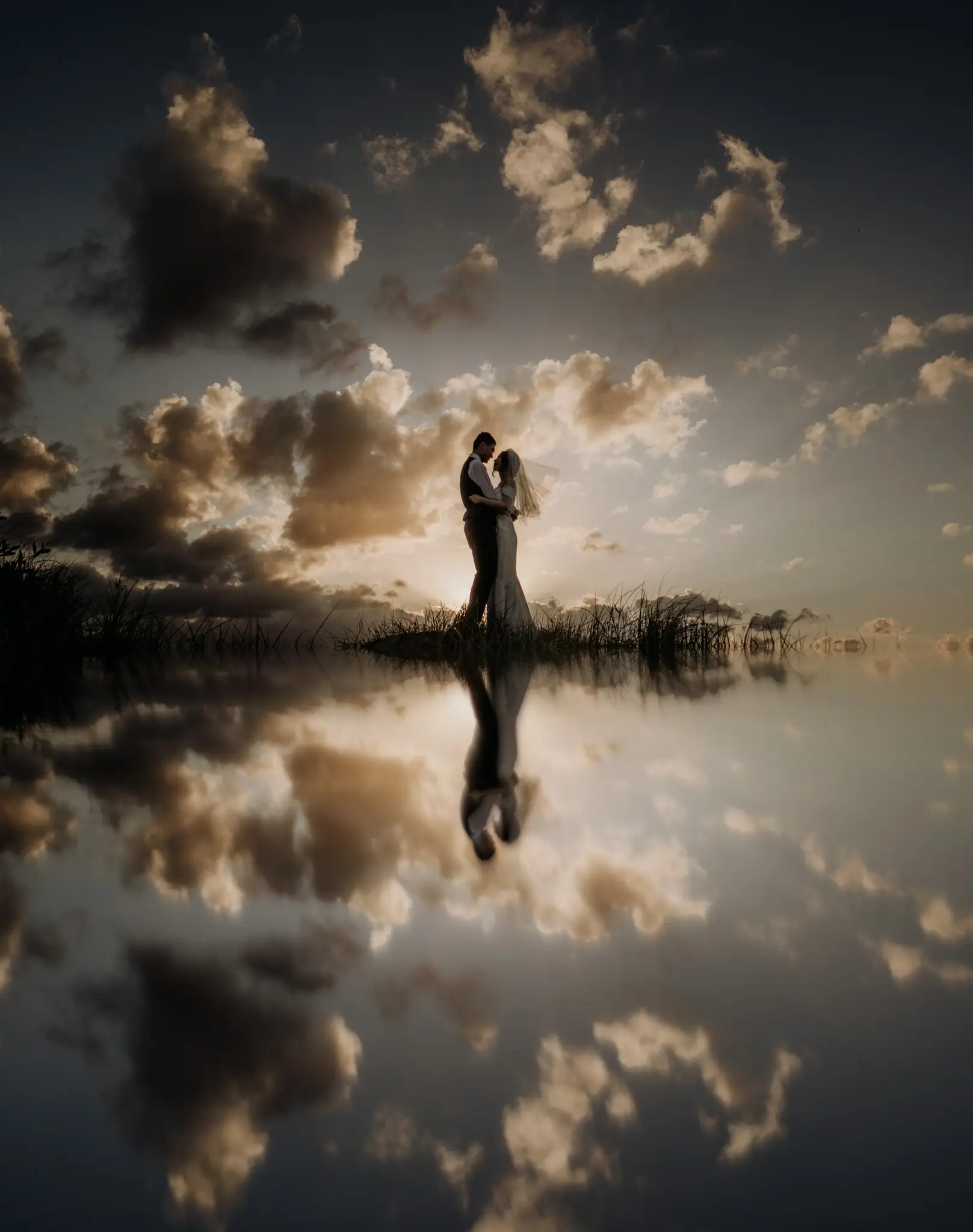 Couple mirrored in still water under a burning sky