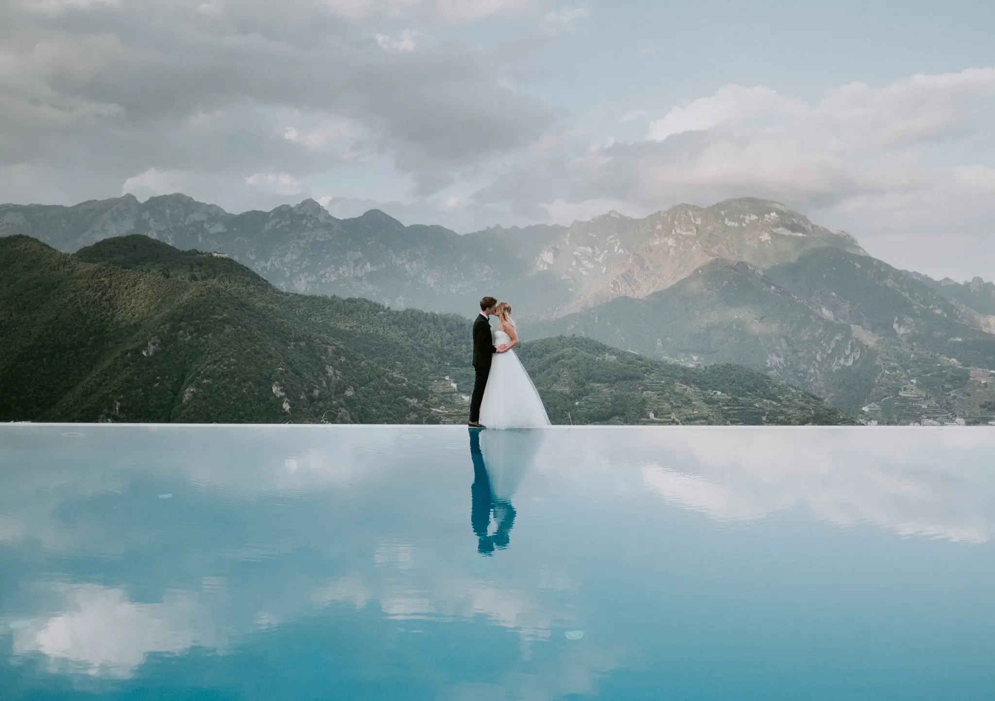 Couple reflected in an infinity pool against the mountains