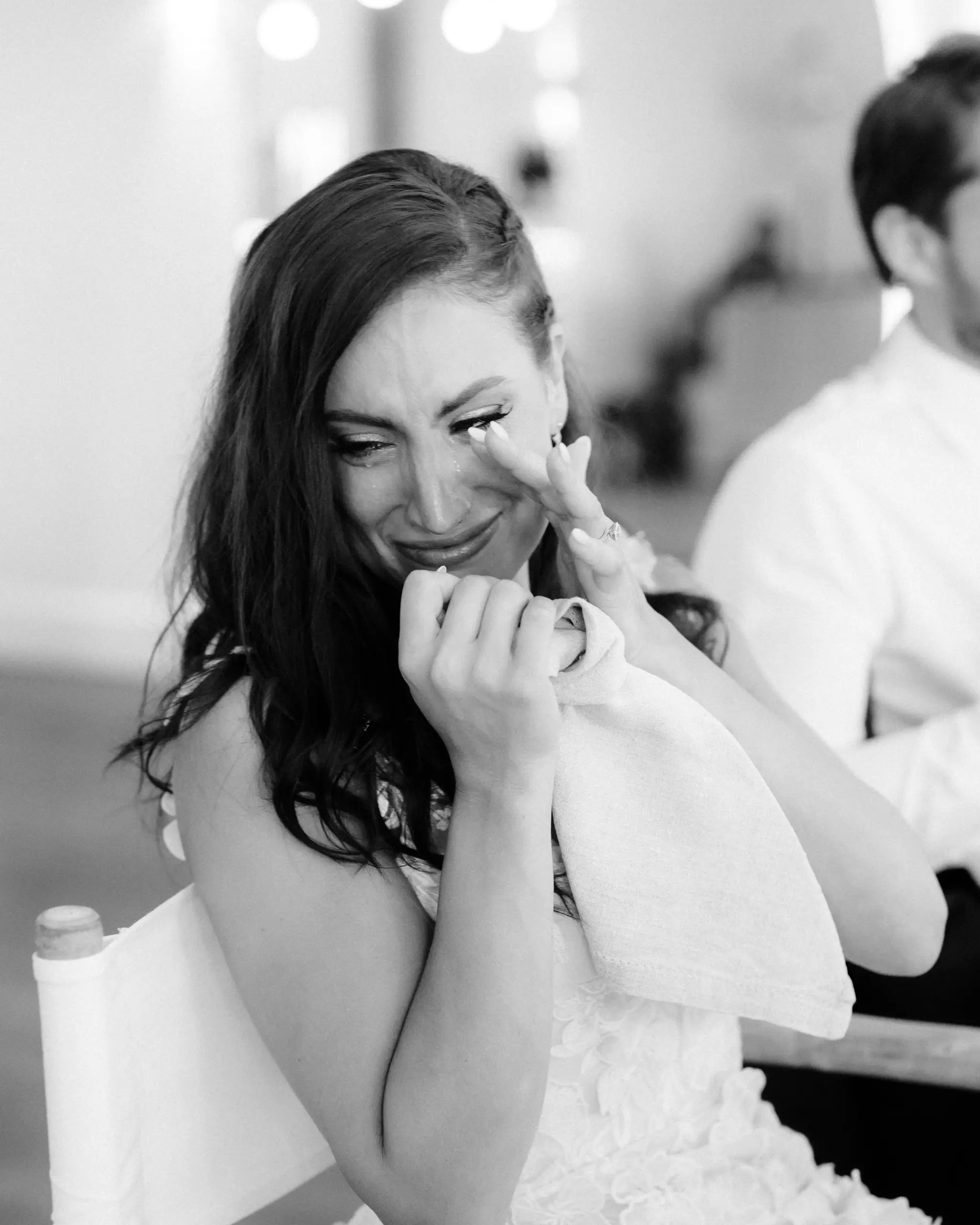Bride laughing through tears in the front row, in black and white
