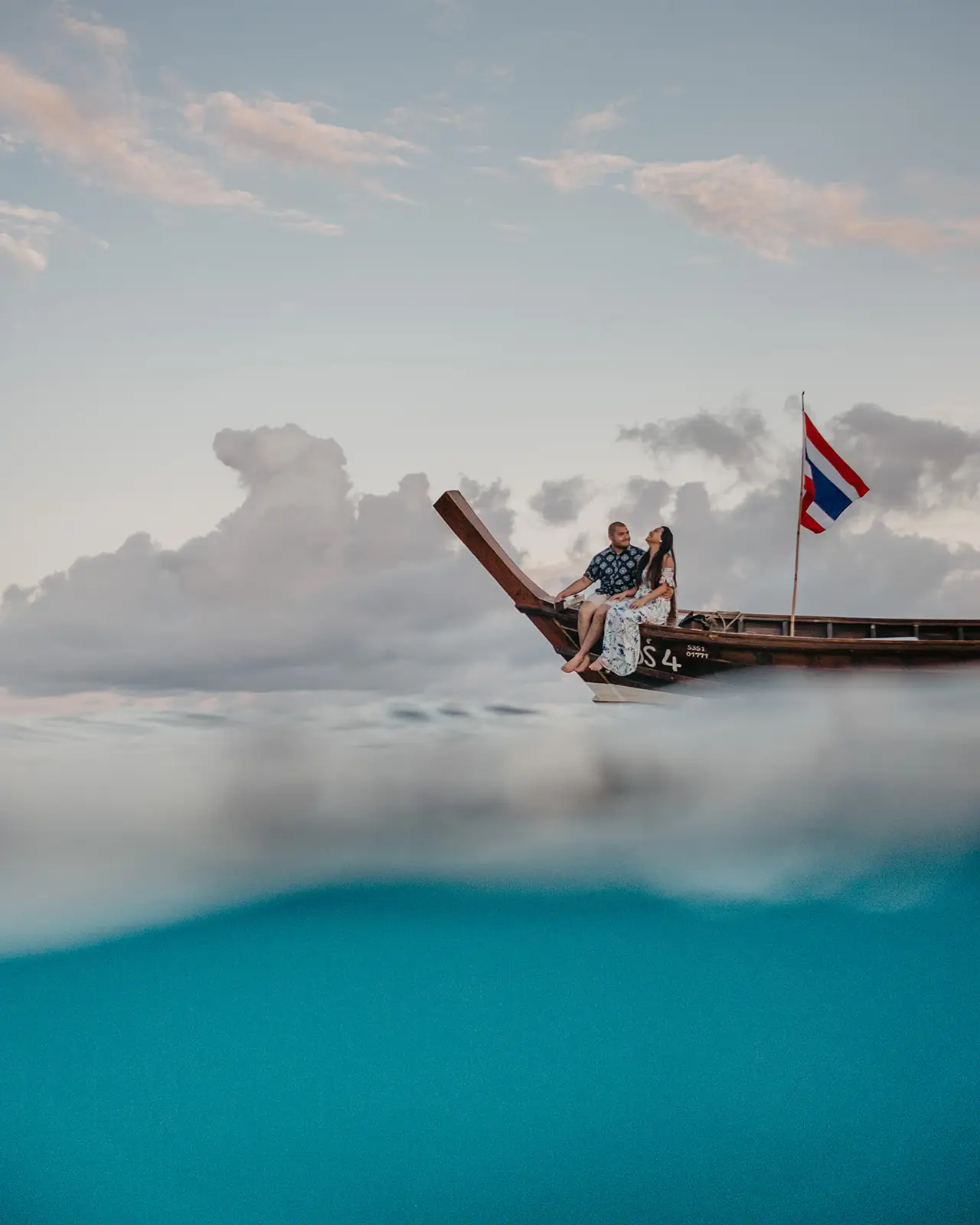 Couple seated on a longtail boat, half beneath the waterline
