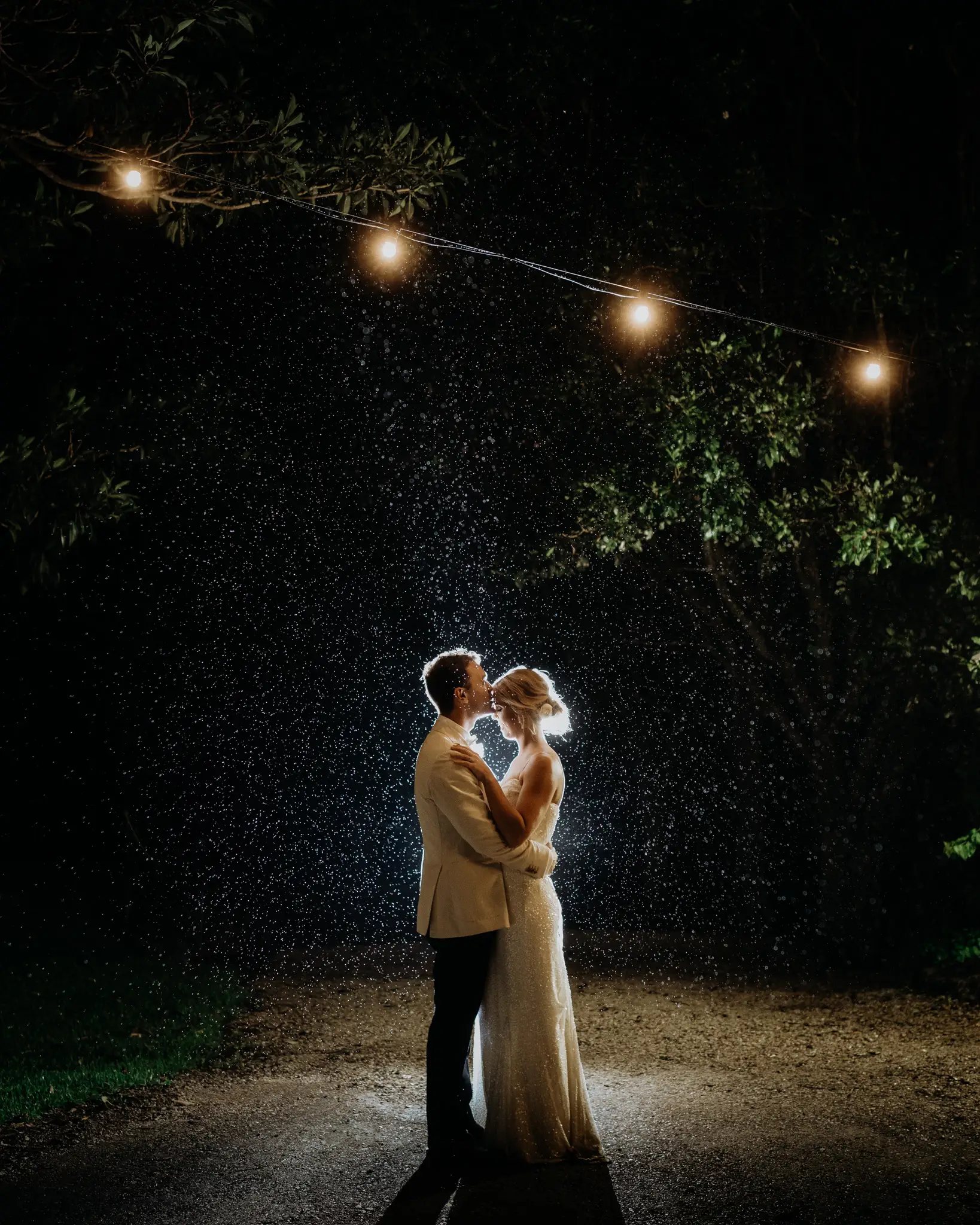 Backlit couple under festoon lights in light rain