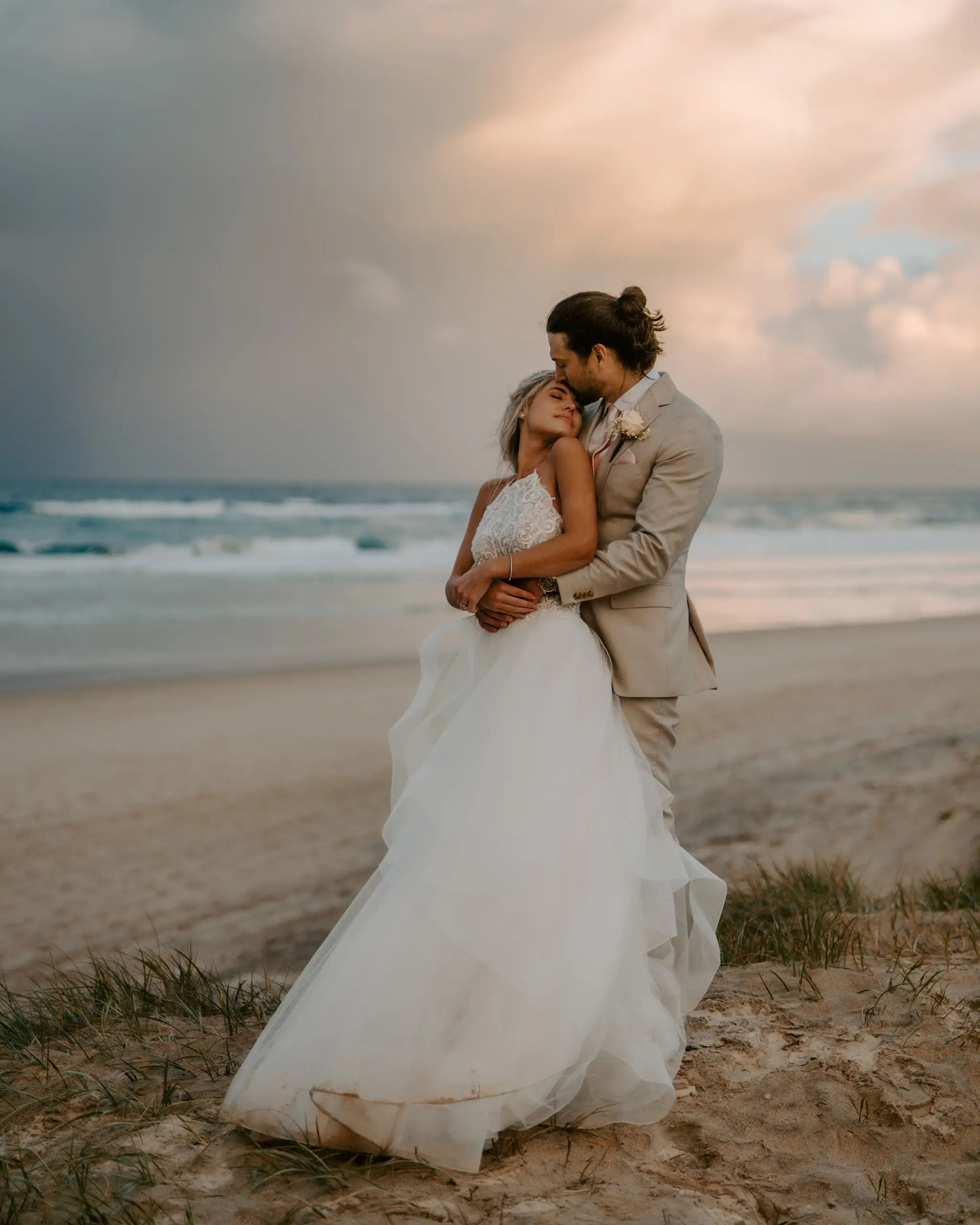 Couple on the dunes under a storm-lit sky