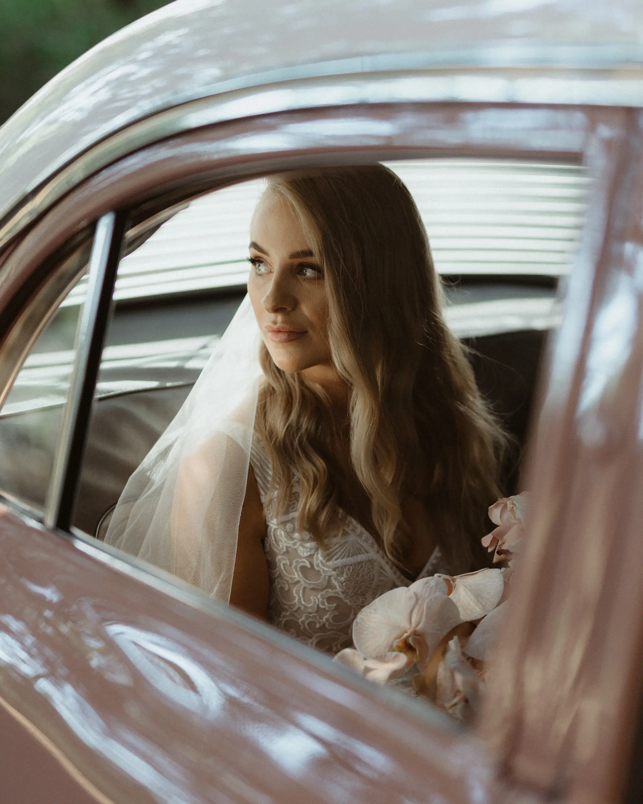 Bride looking out from the window of a vintage car