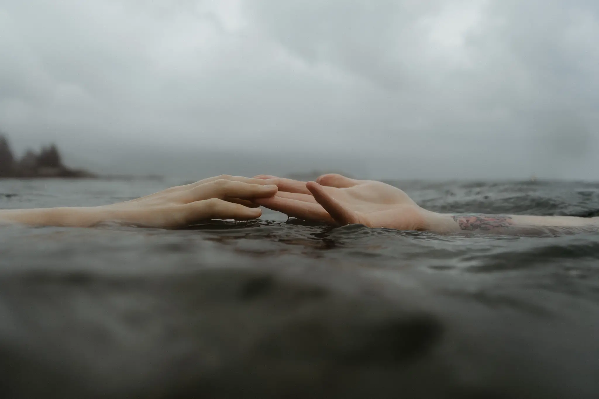 The couple's hands resting together on the surface of the sea