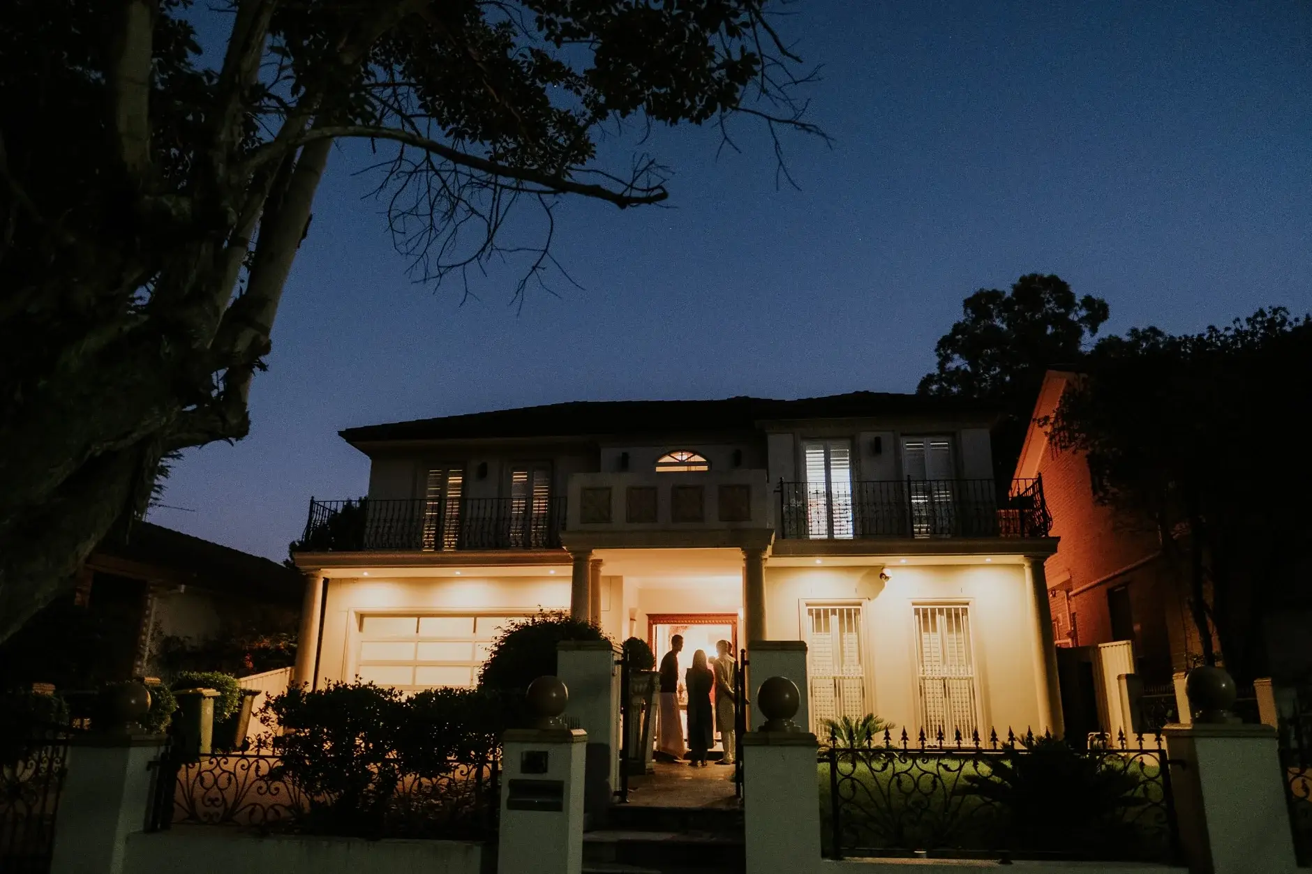 The family home lit up at dusk on the eve of the wedding, Sydney