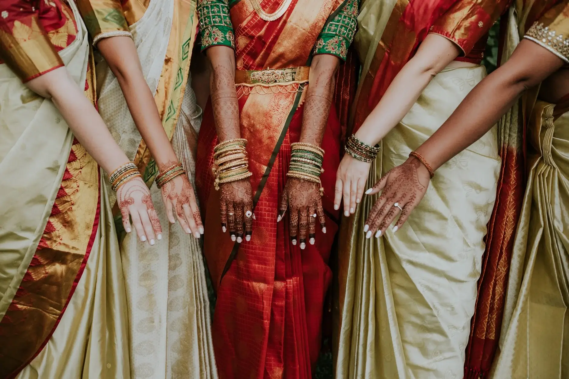 The bridesmaids’ hennaed hands and bangles against their saris