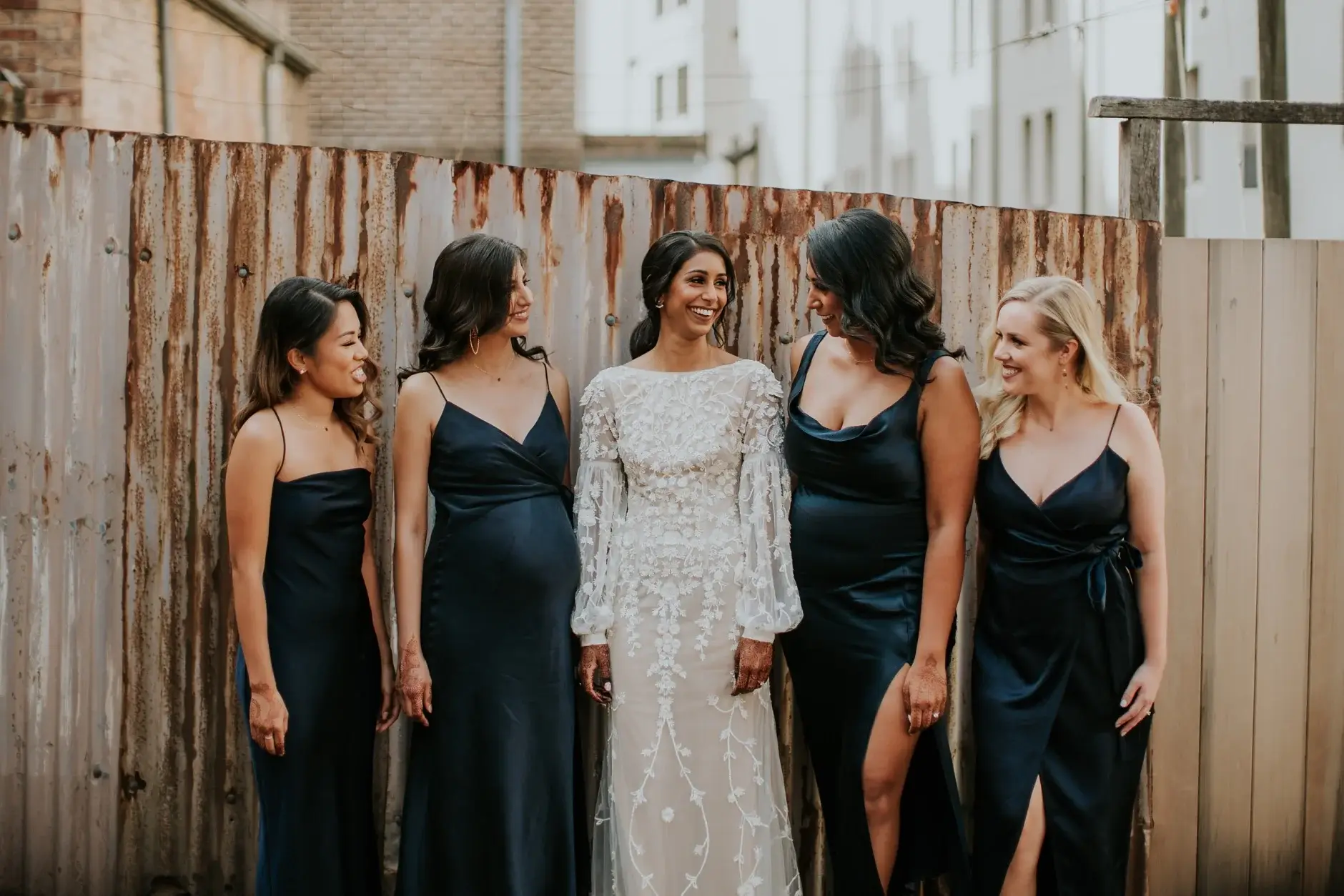 Priyanka with her bridesmaids in navy against the timber fence