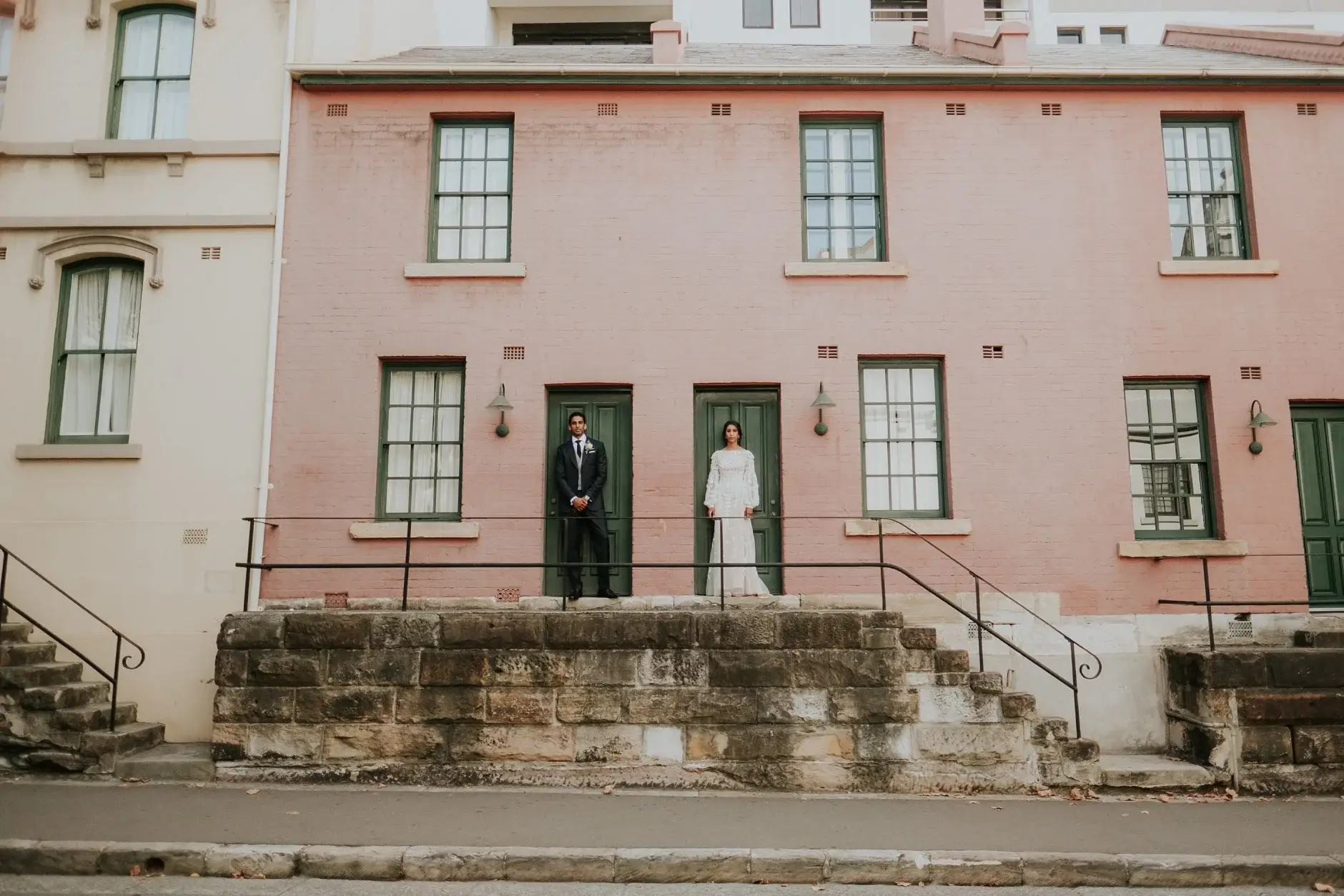 The couple tiny in the doorway of a pink terrace, The Rocks