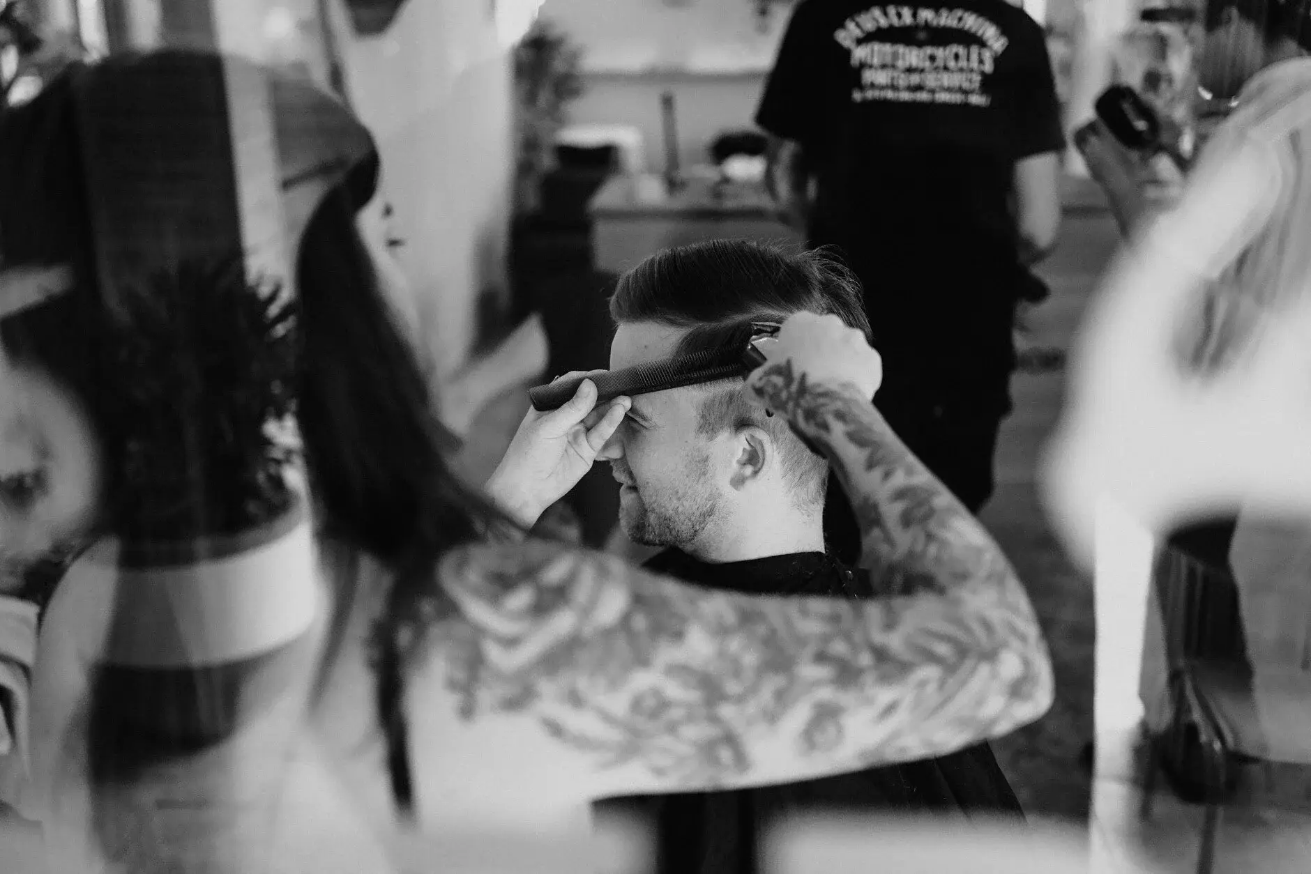 A tattooed hand reaching for the clippers in the barber shop, Byron Bay