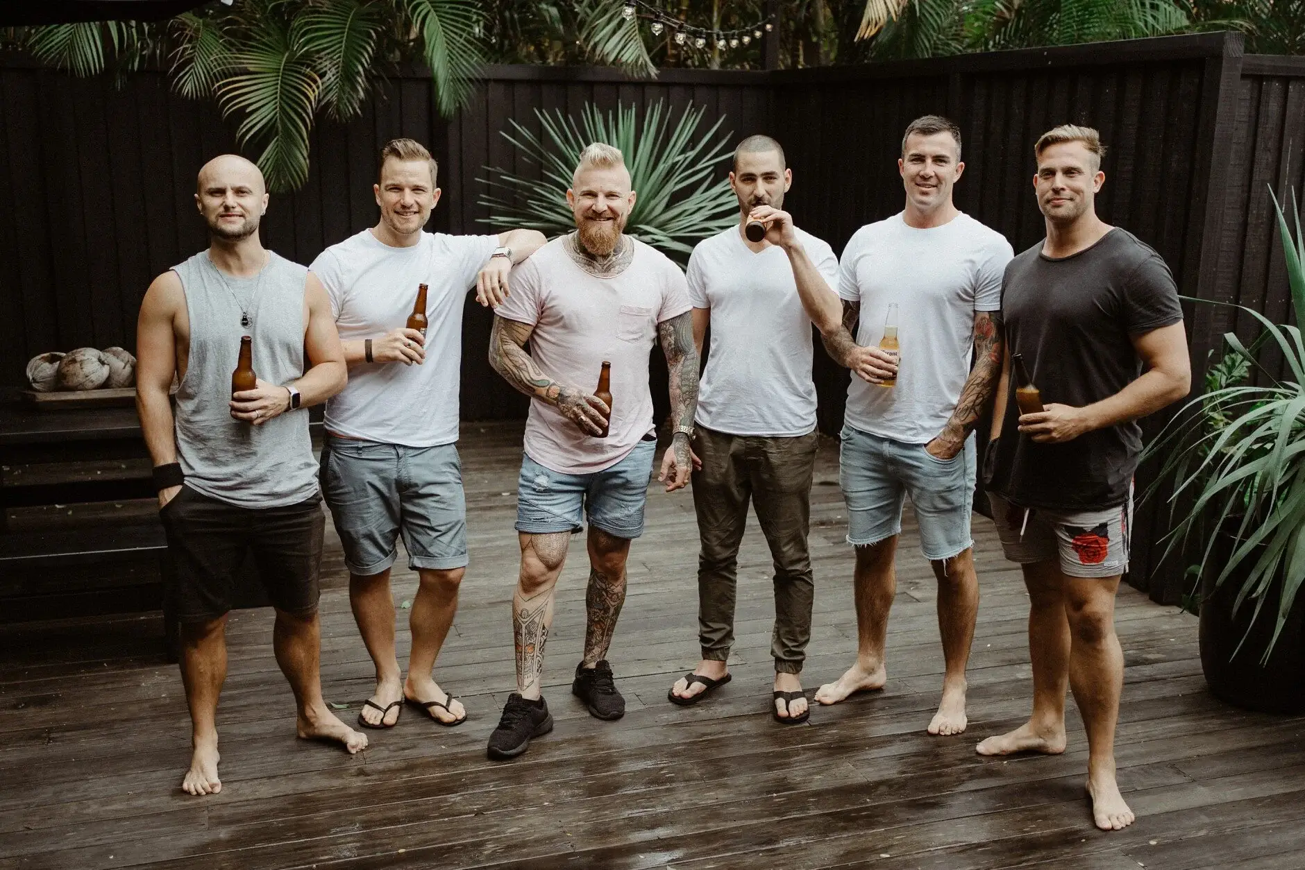 The groomsmen barefoot in shorts with a drink before getting dressed, Byron Bay