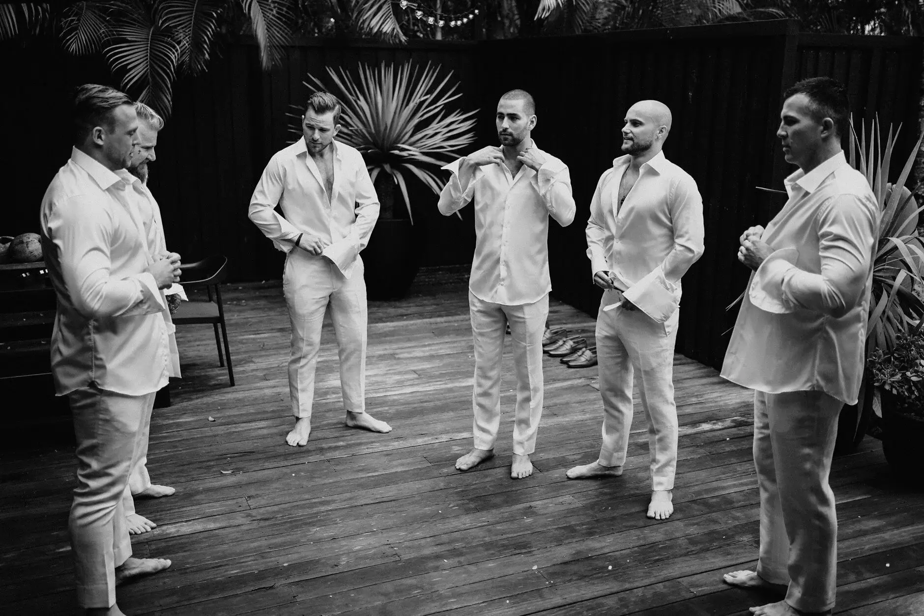 Matt and the groomsmen buttoning their shirts in the garden at dusk light, Byron Bay