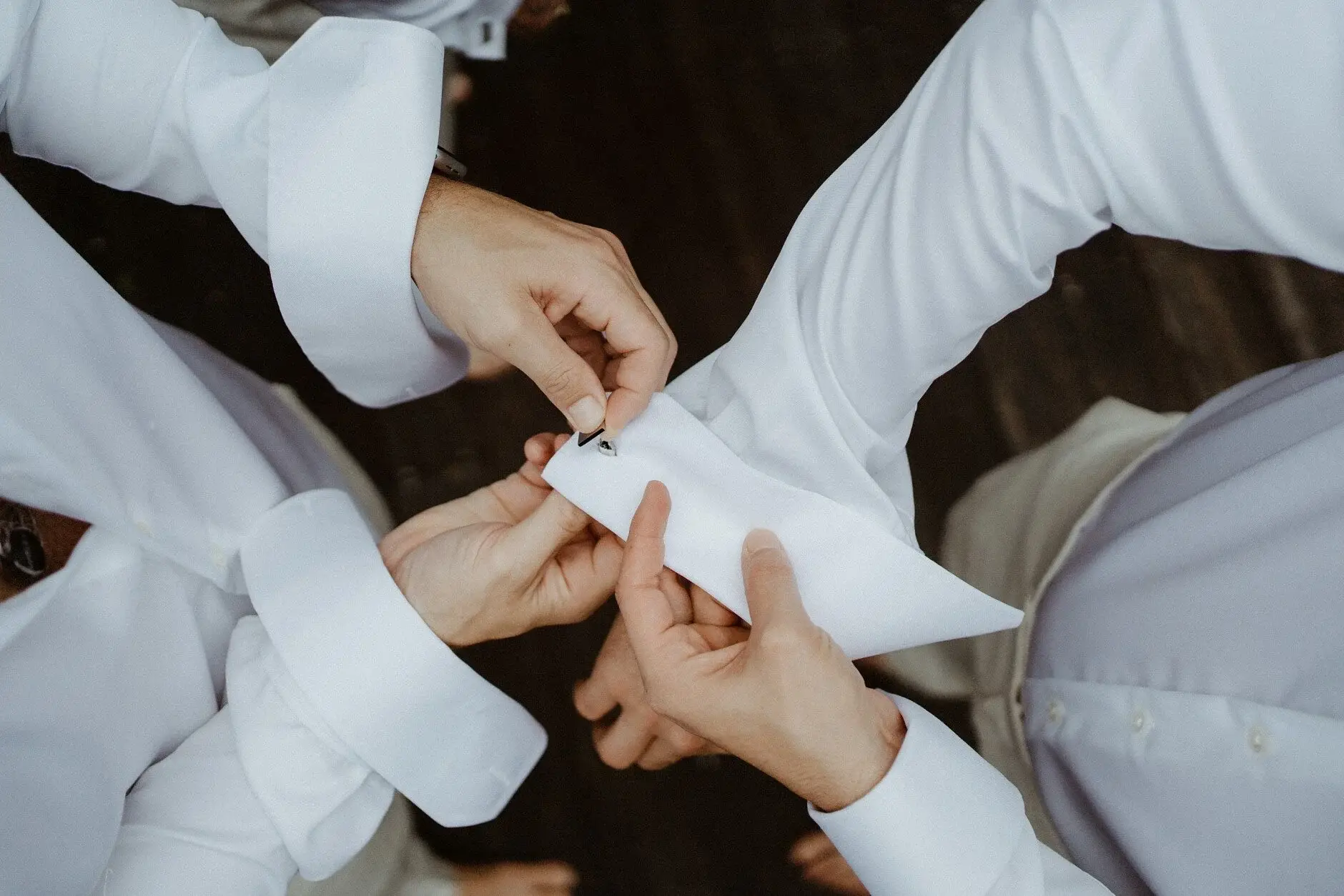 Hands clustered together helping with a buttonhole, Byron Bay