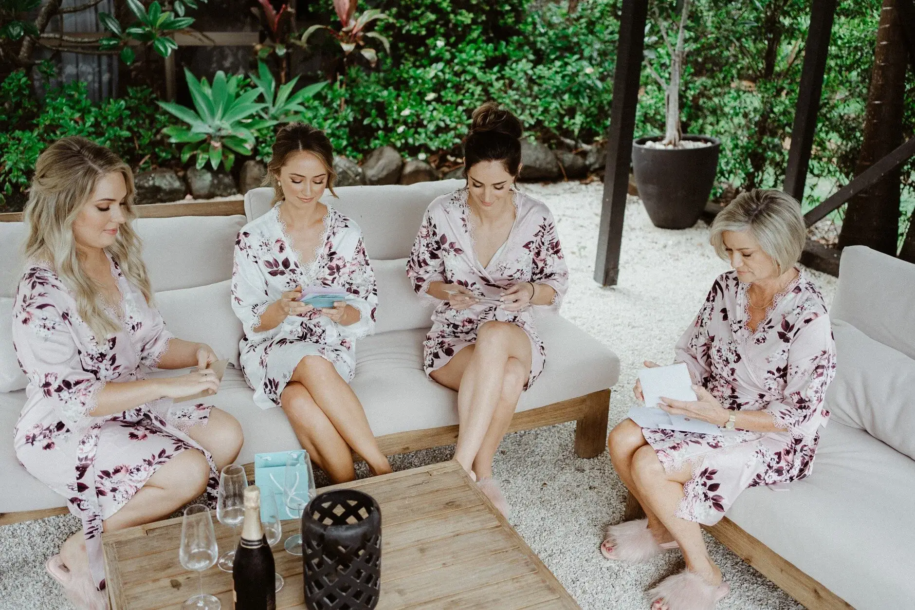 The bridesmaids sitting together in floral robes on the couch, Byron Bay