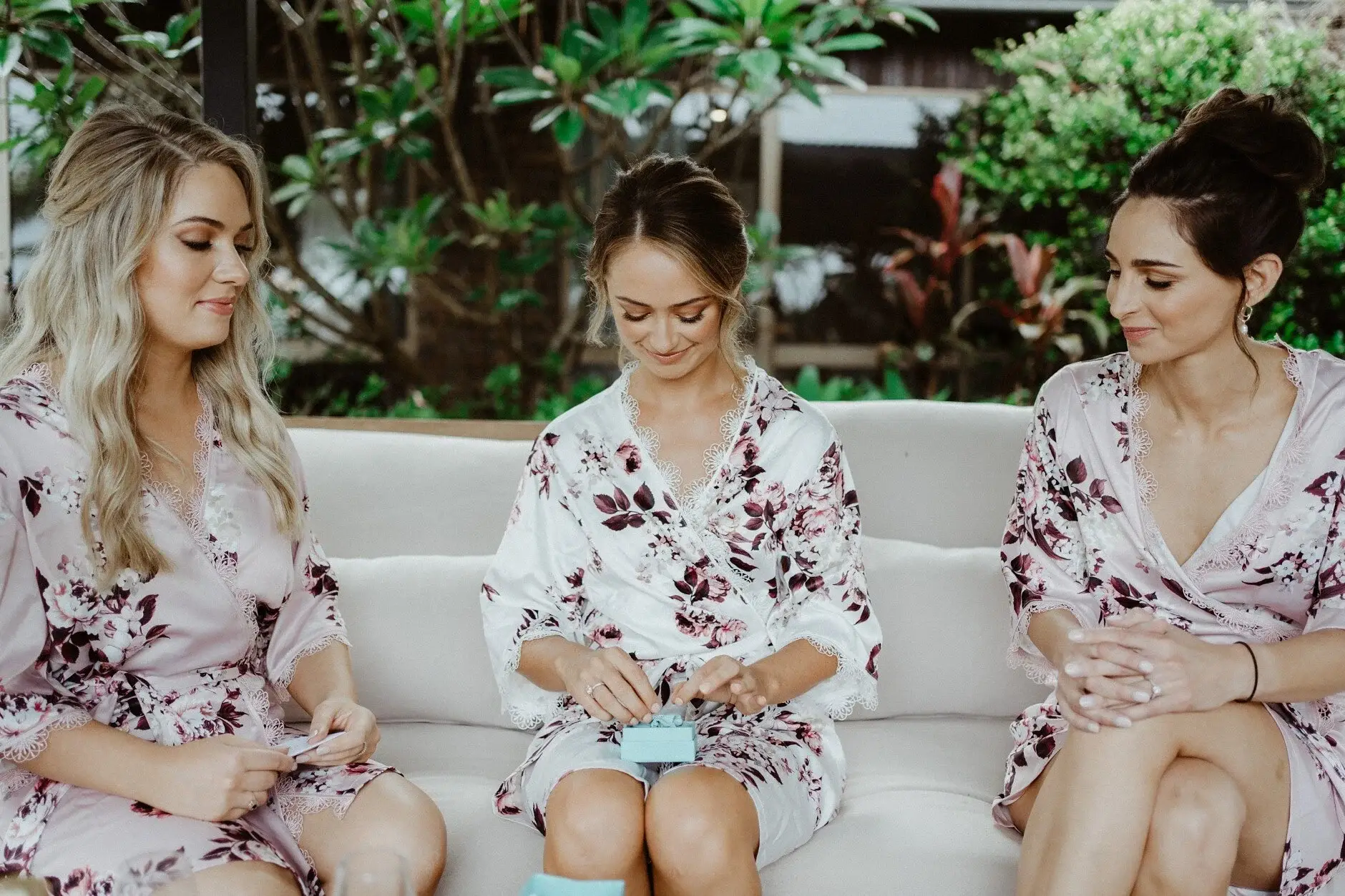 The bridesmaids in floral robes laughing together on the couch, Byron Bay
