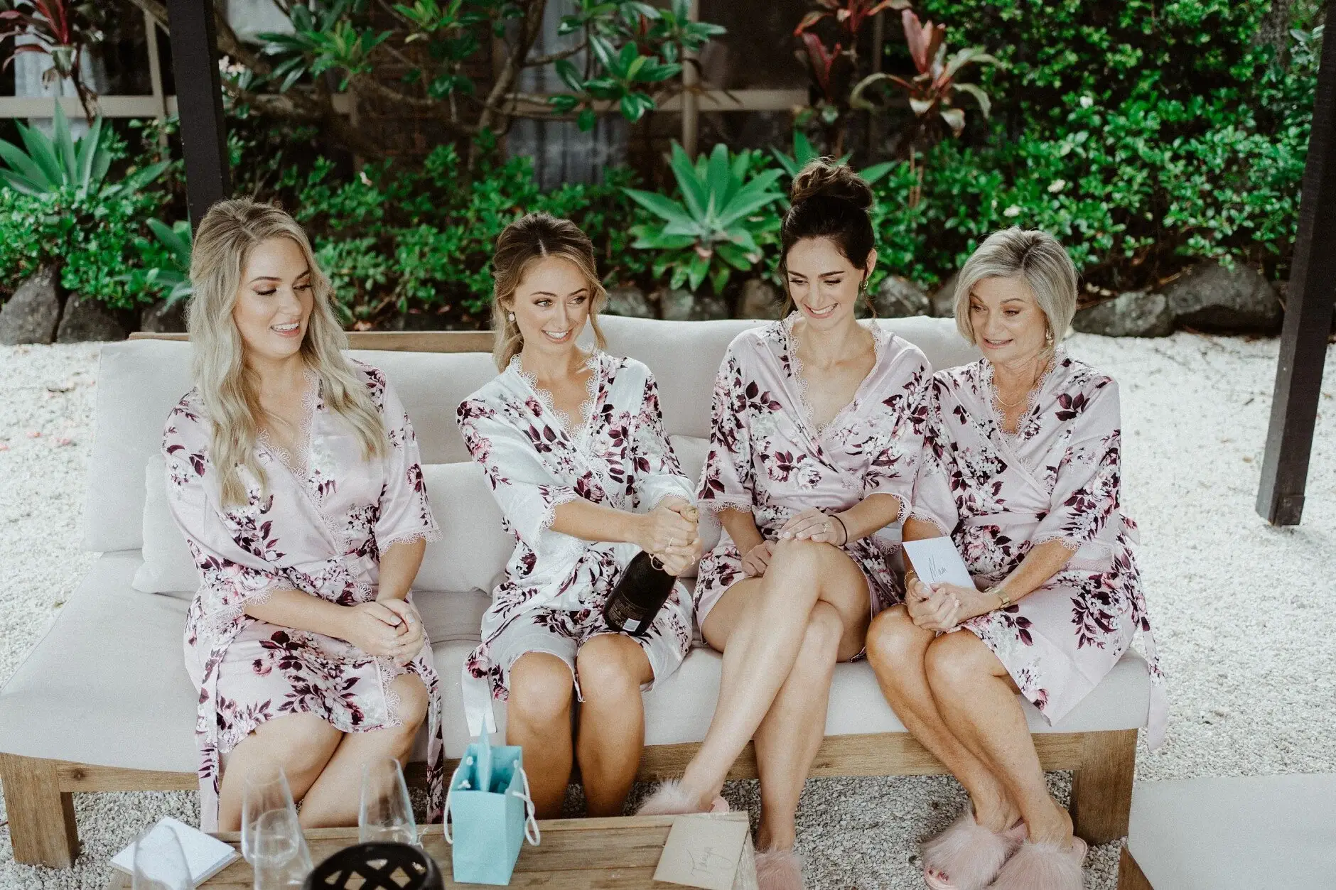 The bridesmaids seated in a row in front of tropical planting, Byron Bay