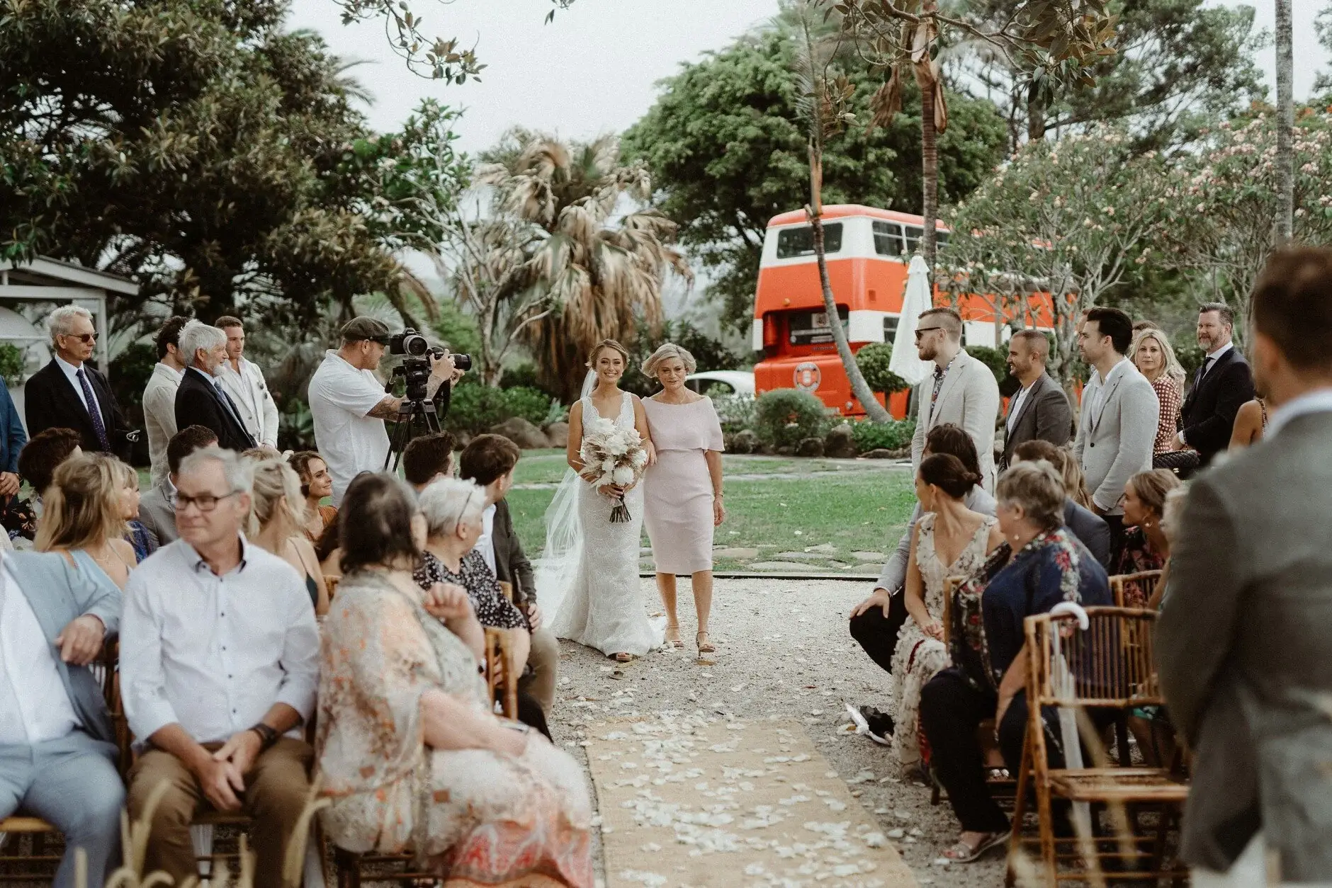 Breanna walking in as guests turn to watch, the red bus behind, The Fig Tree Byron Bay
