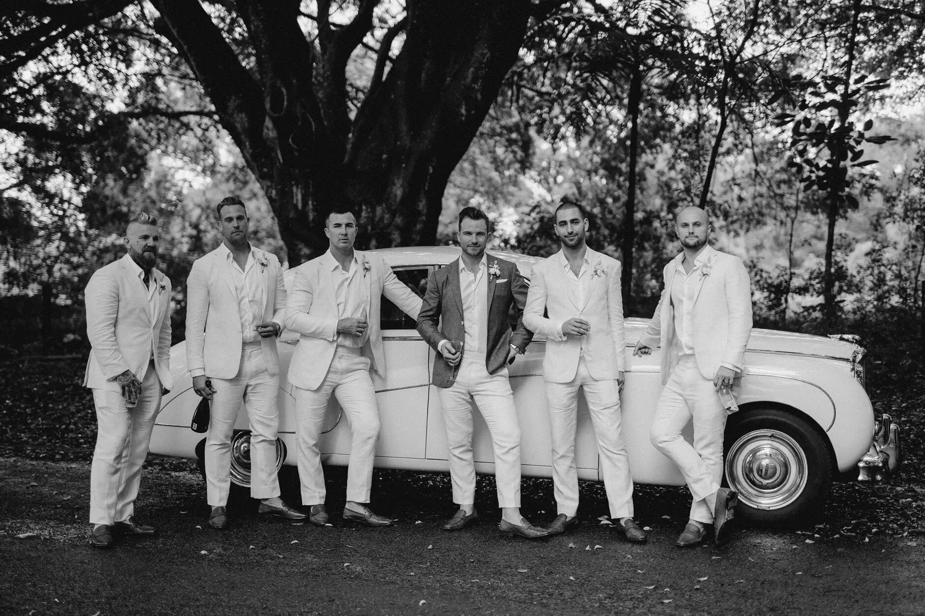 The bridal party gathered around the vintage car, black and white, Byron Bay