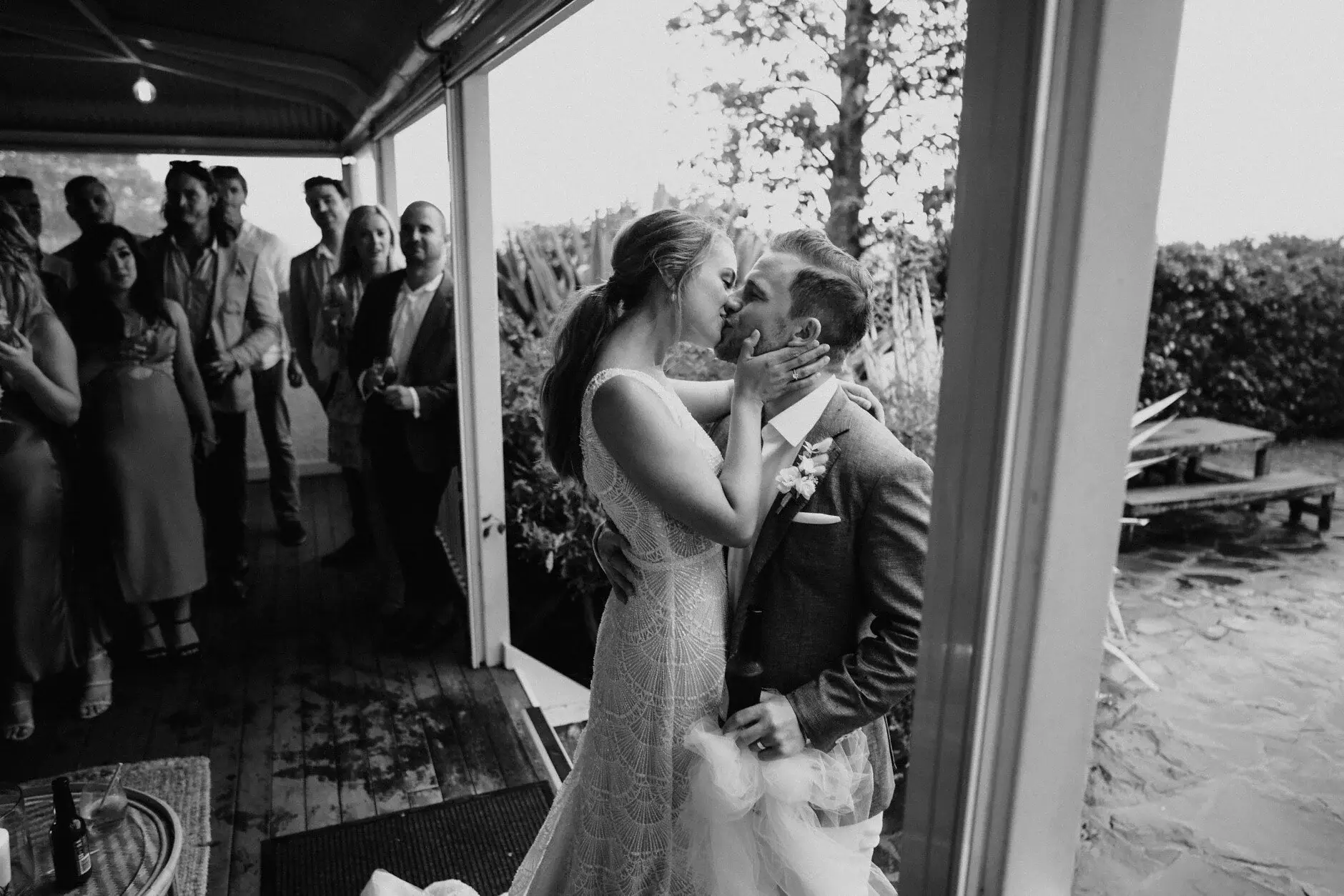 A black-and-white frame of Breanna hugging a guest on the verandah, Byron View Farm