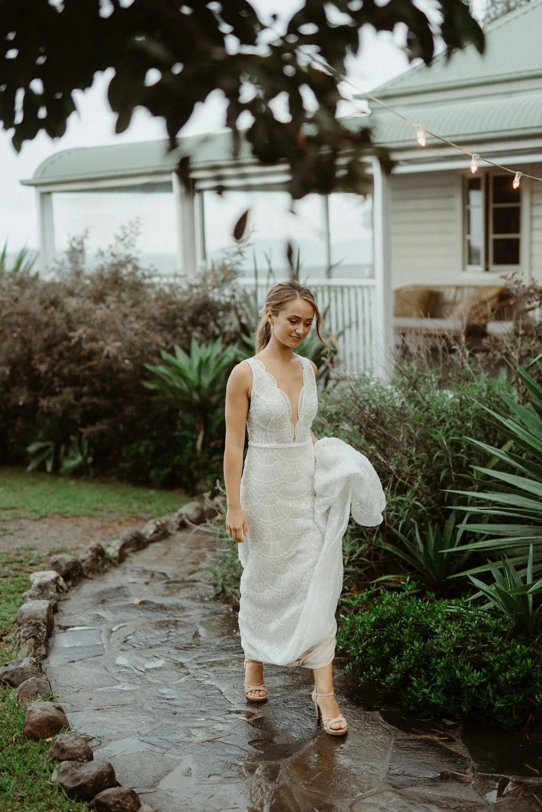 Breanna standing on the wet path in front of the farmhouse, Byron View Farm