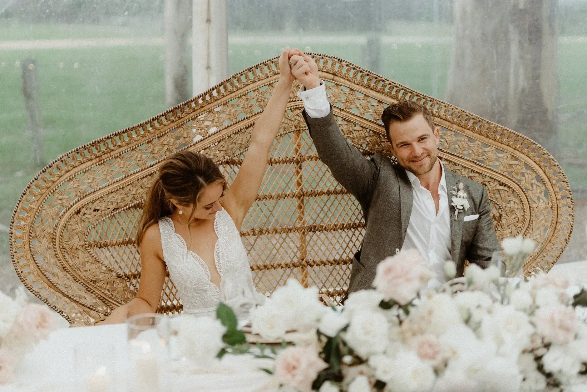 Breanna and Matt toasting behind a woven screen and flowers, Byron View Farm