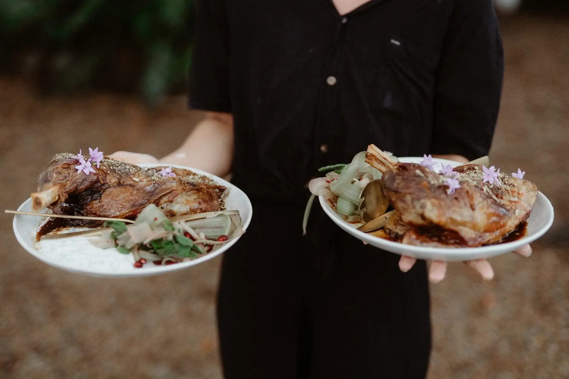 A waiter carrying two plated courses to the table, Byron View Farm