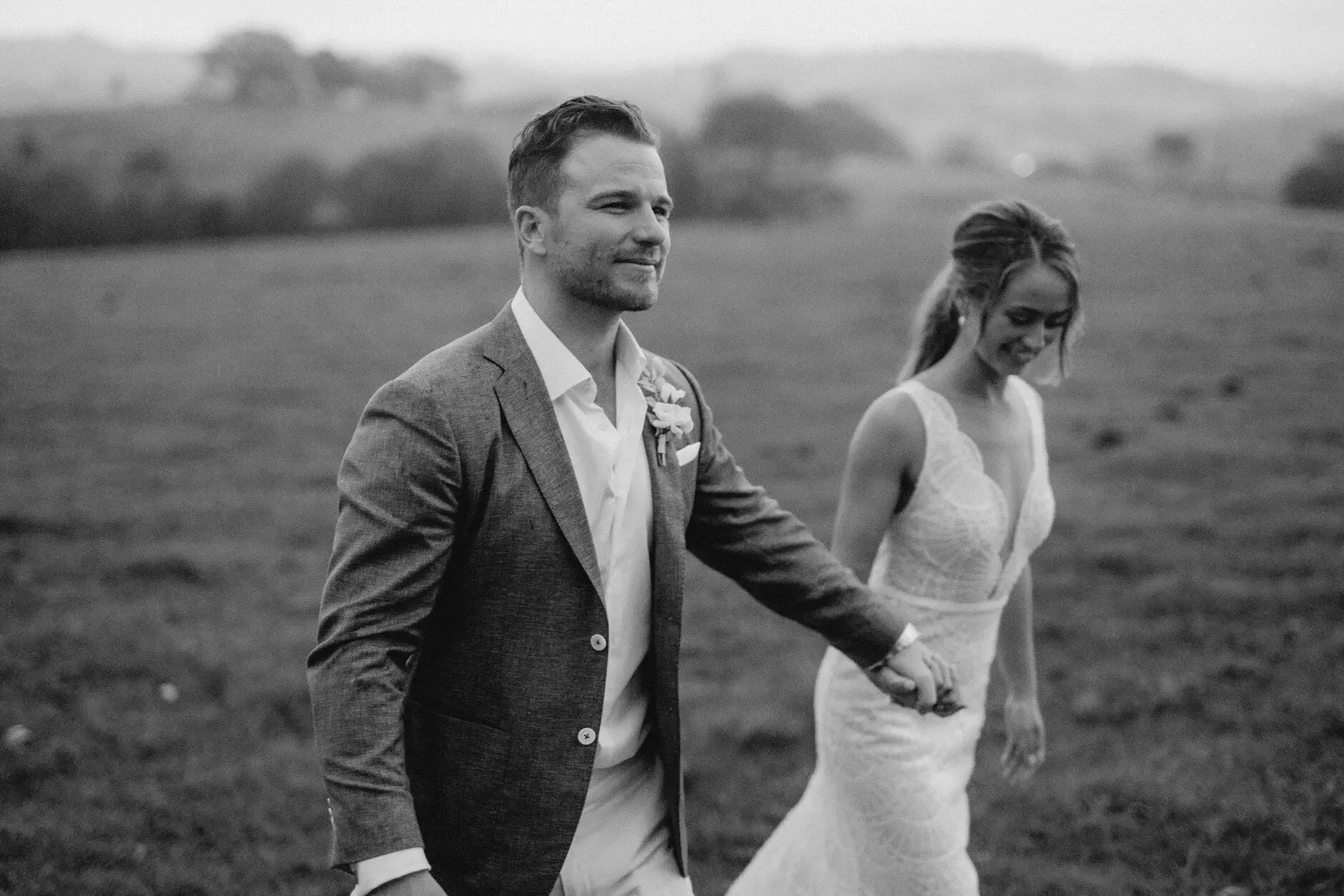 A black-and-white frame of the couple walking the paddock, Byron View Farm